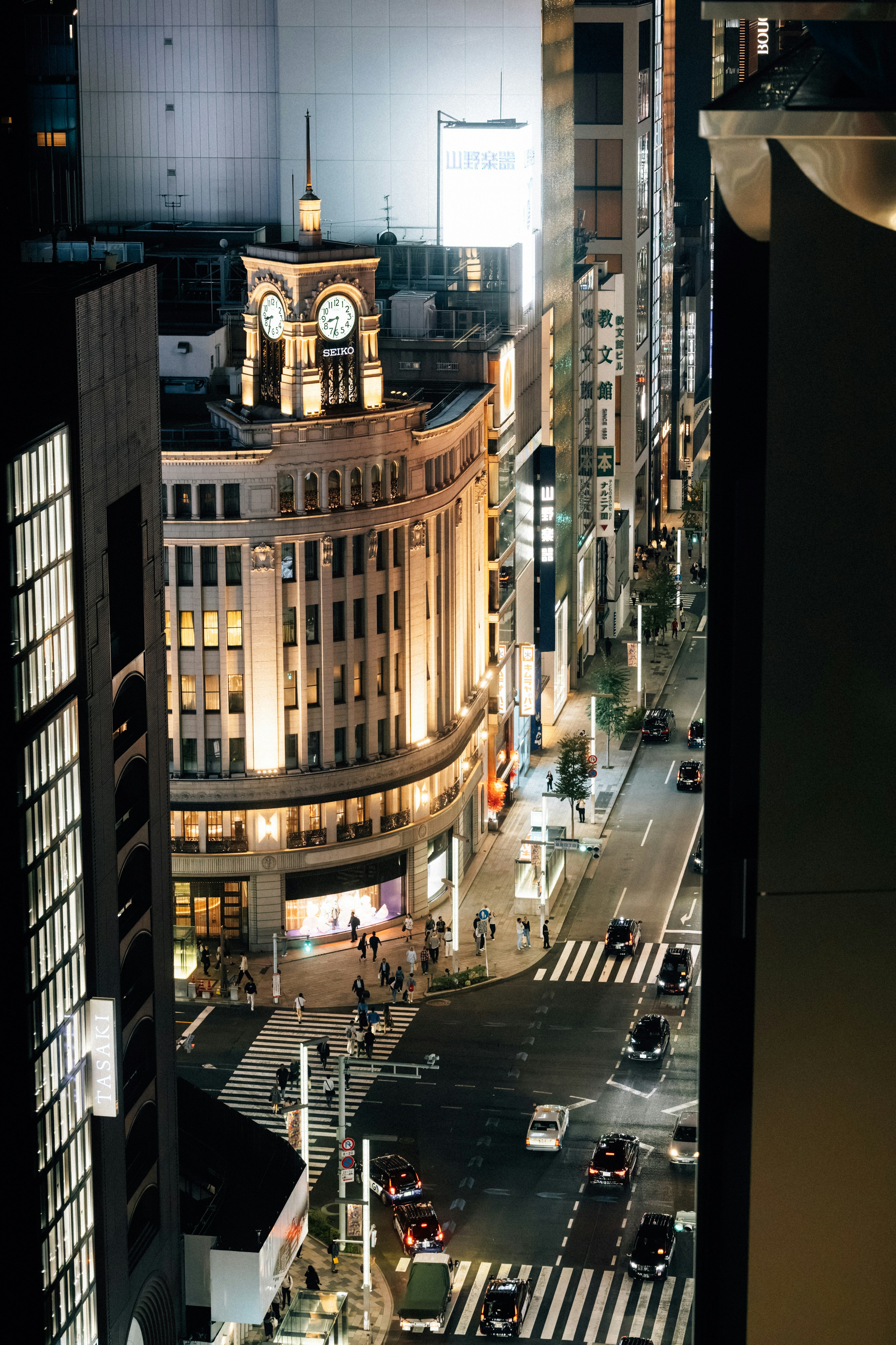 A bustling city street at night with illuminated buildings.