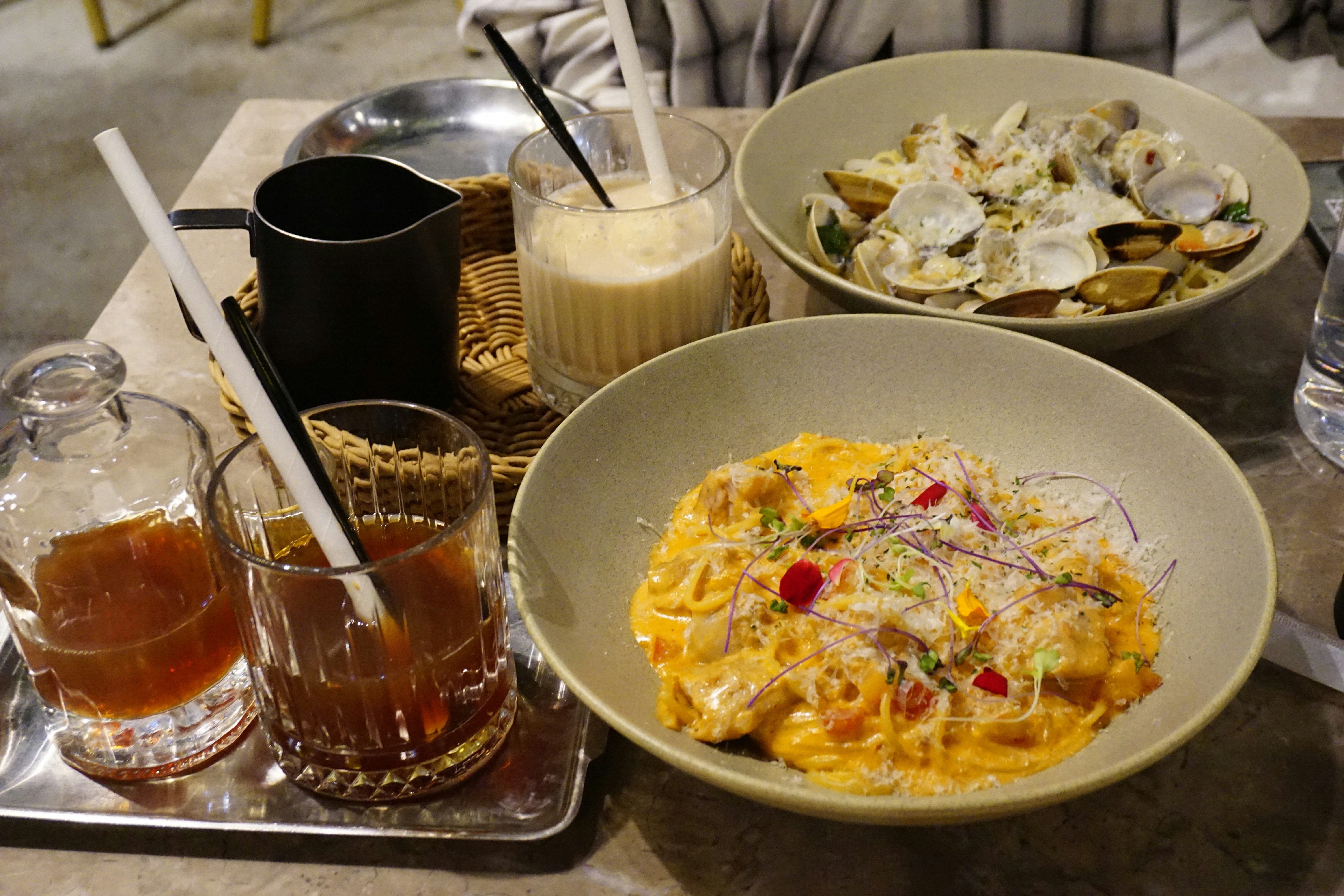 Two pasta dishes and drinks on a table
