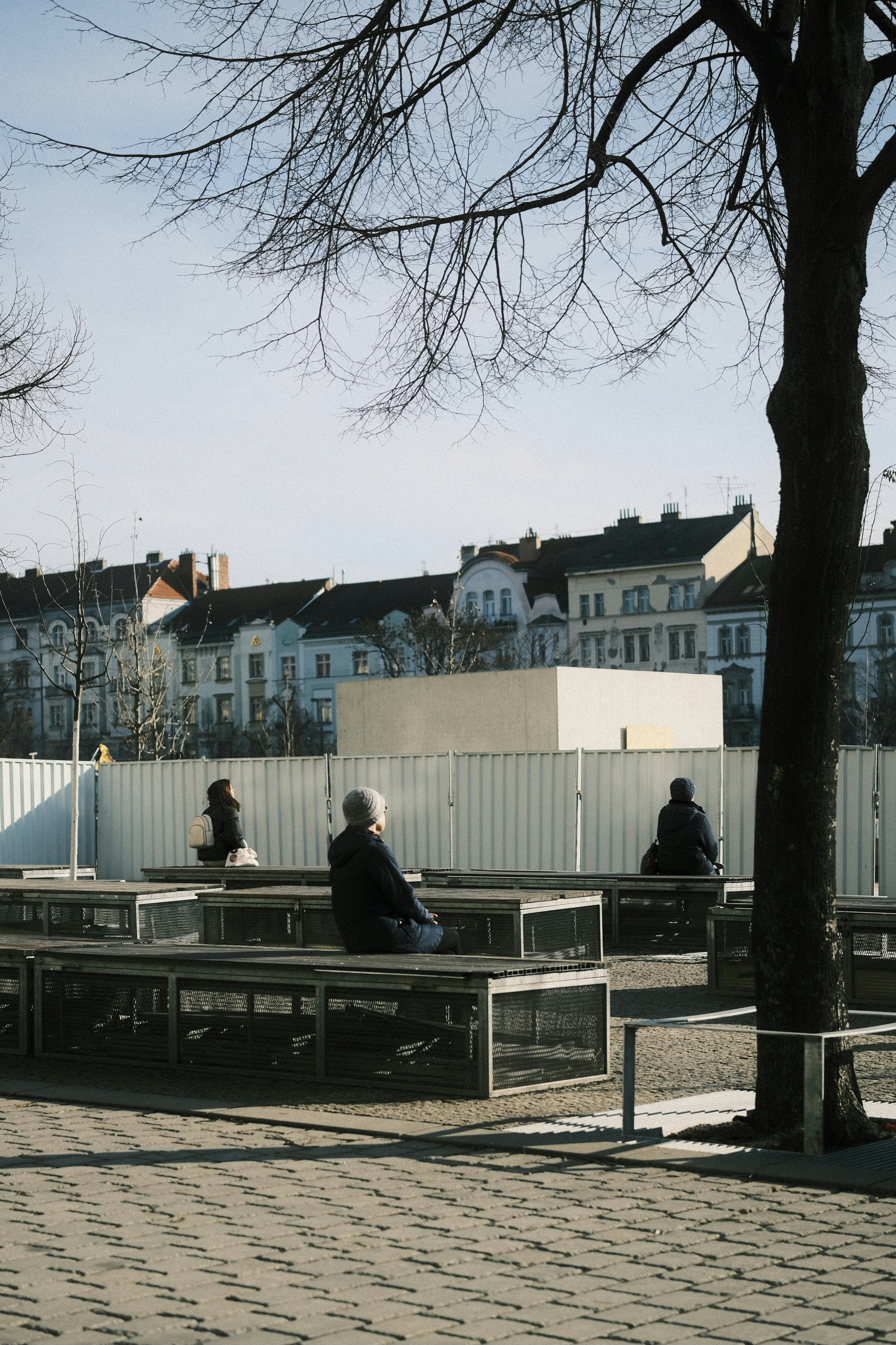 Menschen sitzen auf Bänken in einem Stadtpark.