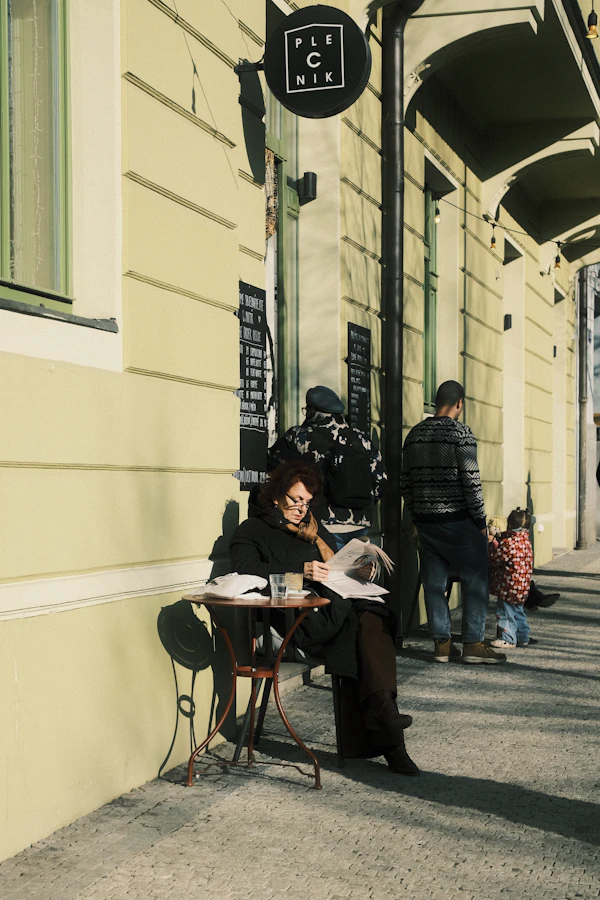 A woman reading a newspaper at an outdoor café table