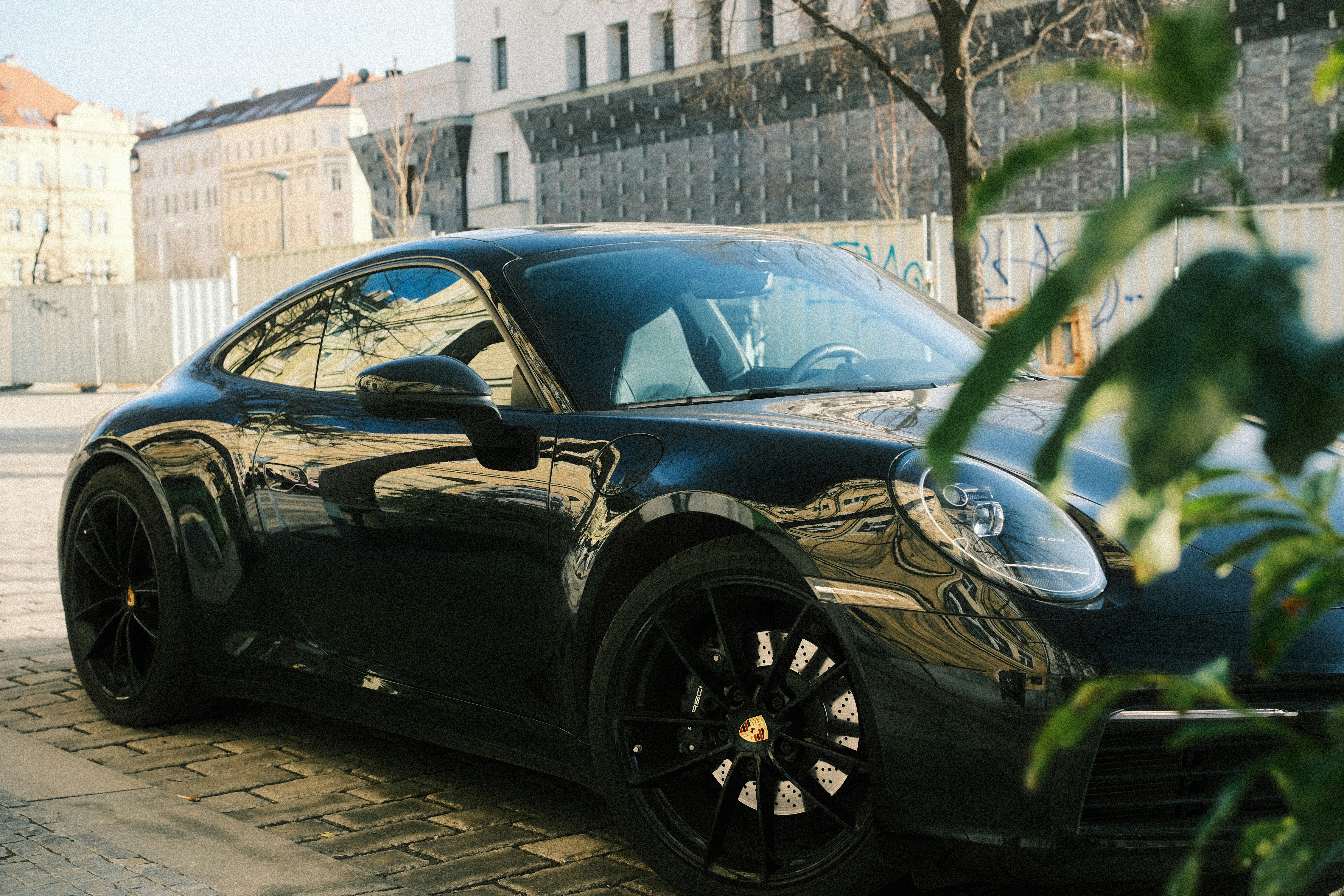 Ein eleganter schwarzer Sportwagen, der auf einer Kopfsteinpflasterstraße geparkt ist.