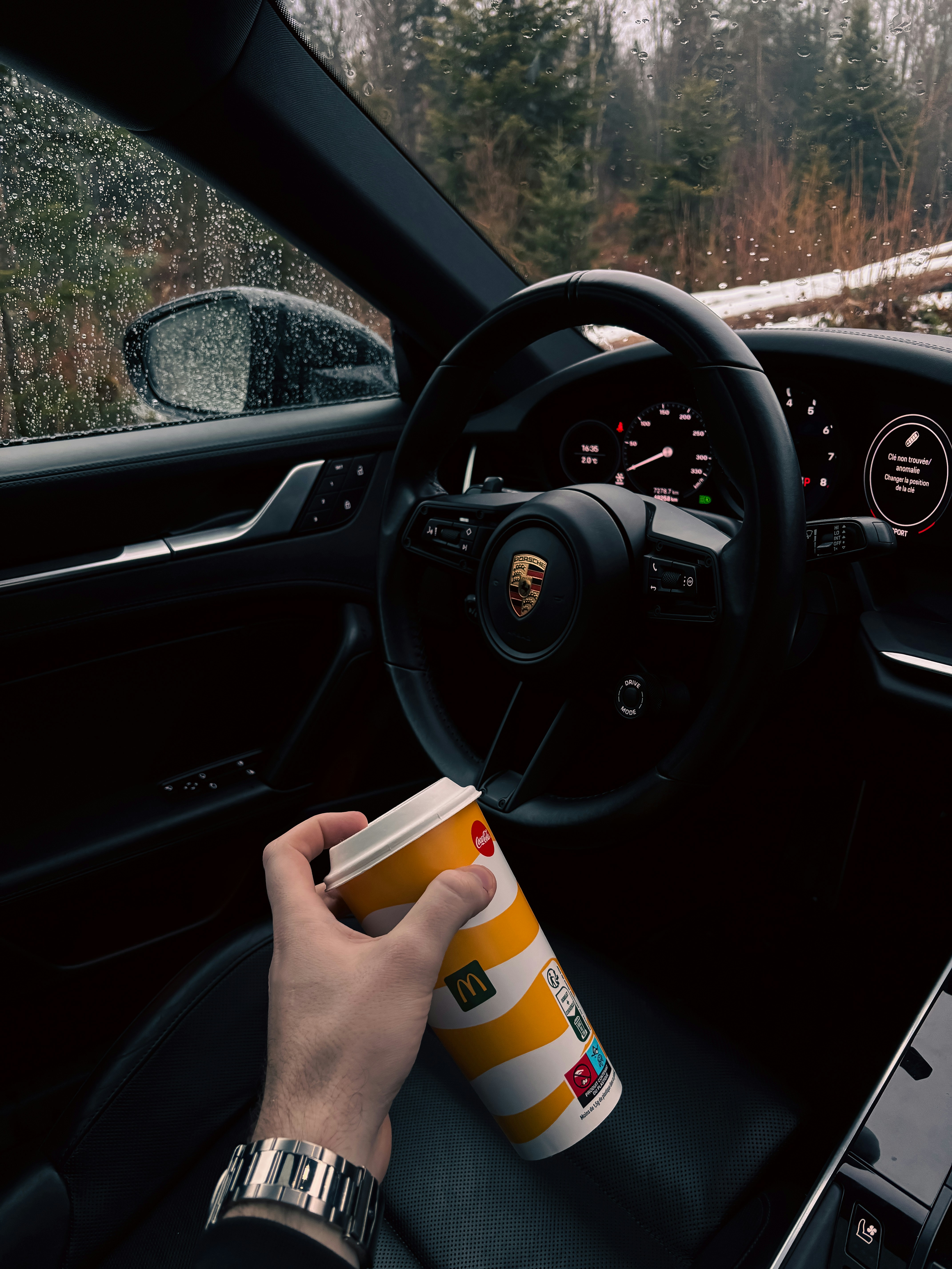 Hand holding mcdonald's cup inside a car