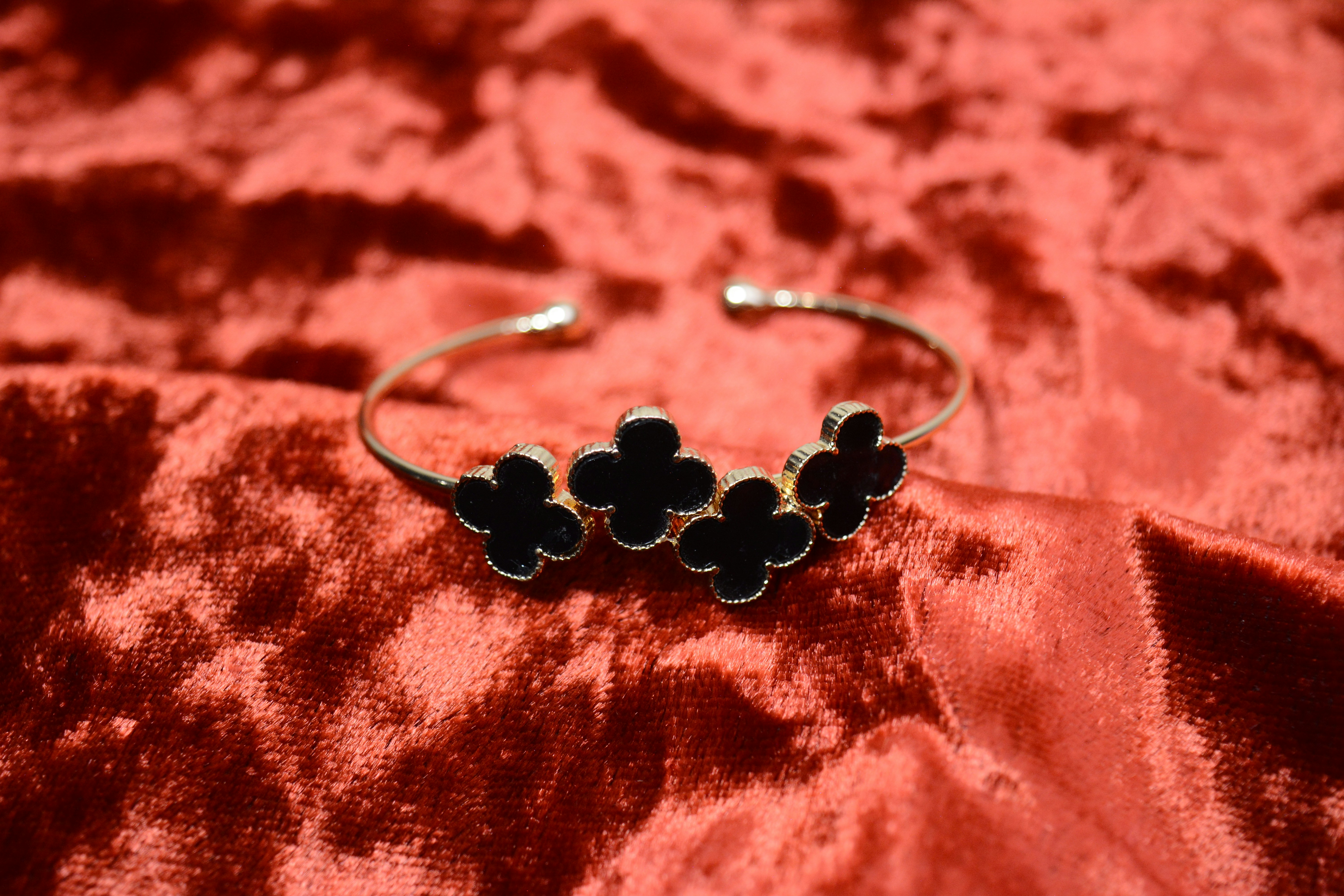 A silver bracelet with four black clover charms.