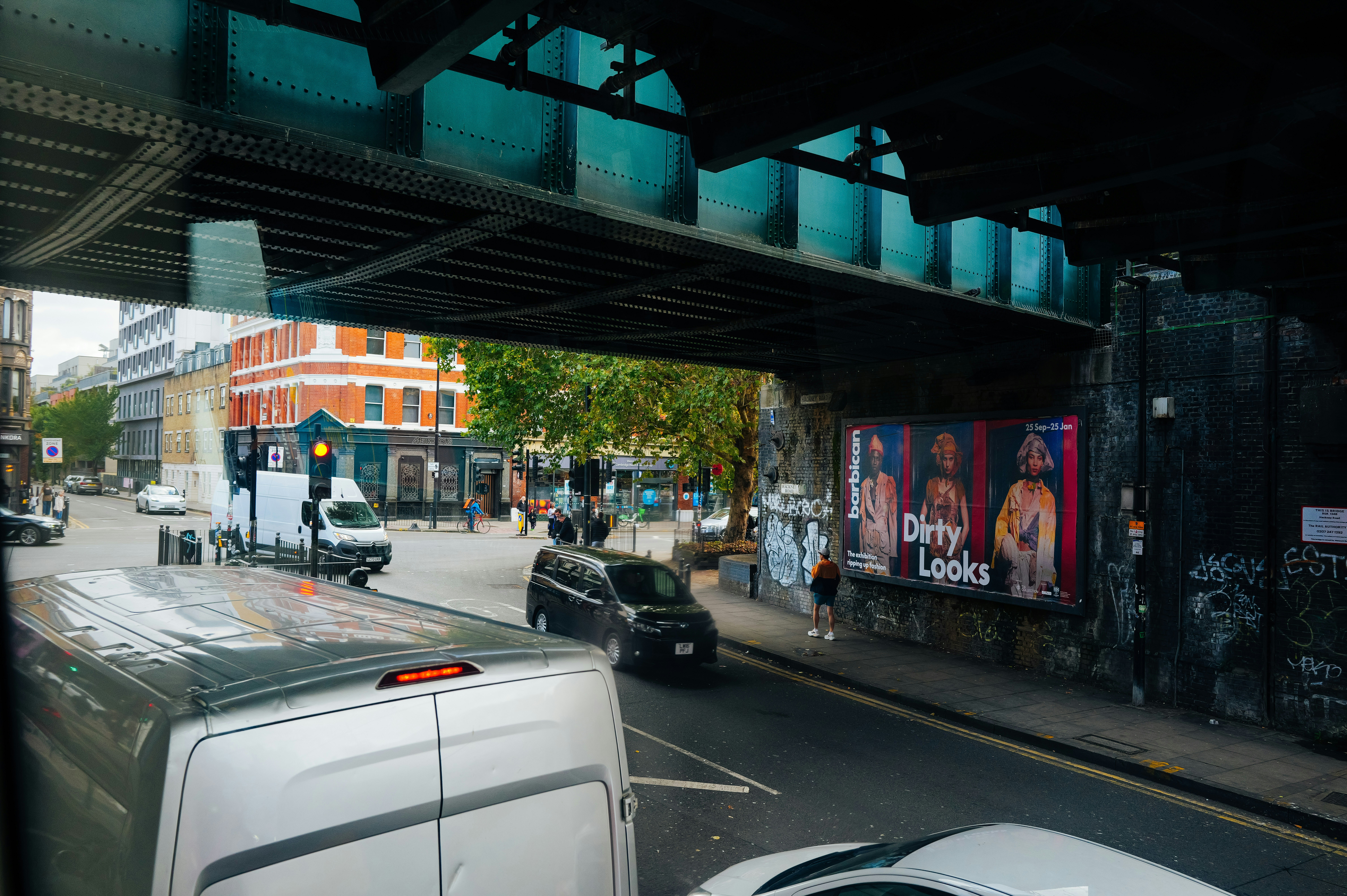Street scene with buildings, vehicles, and a large poster.