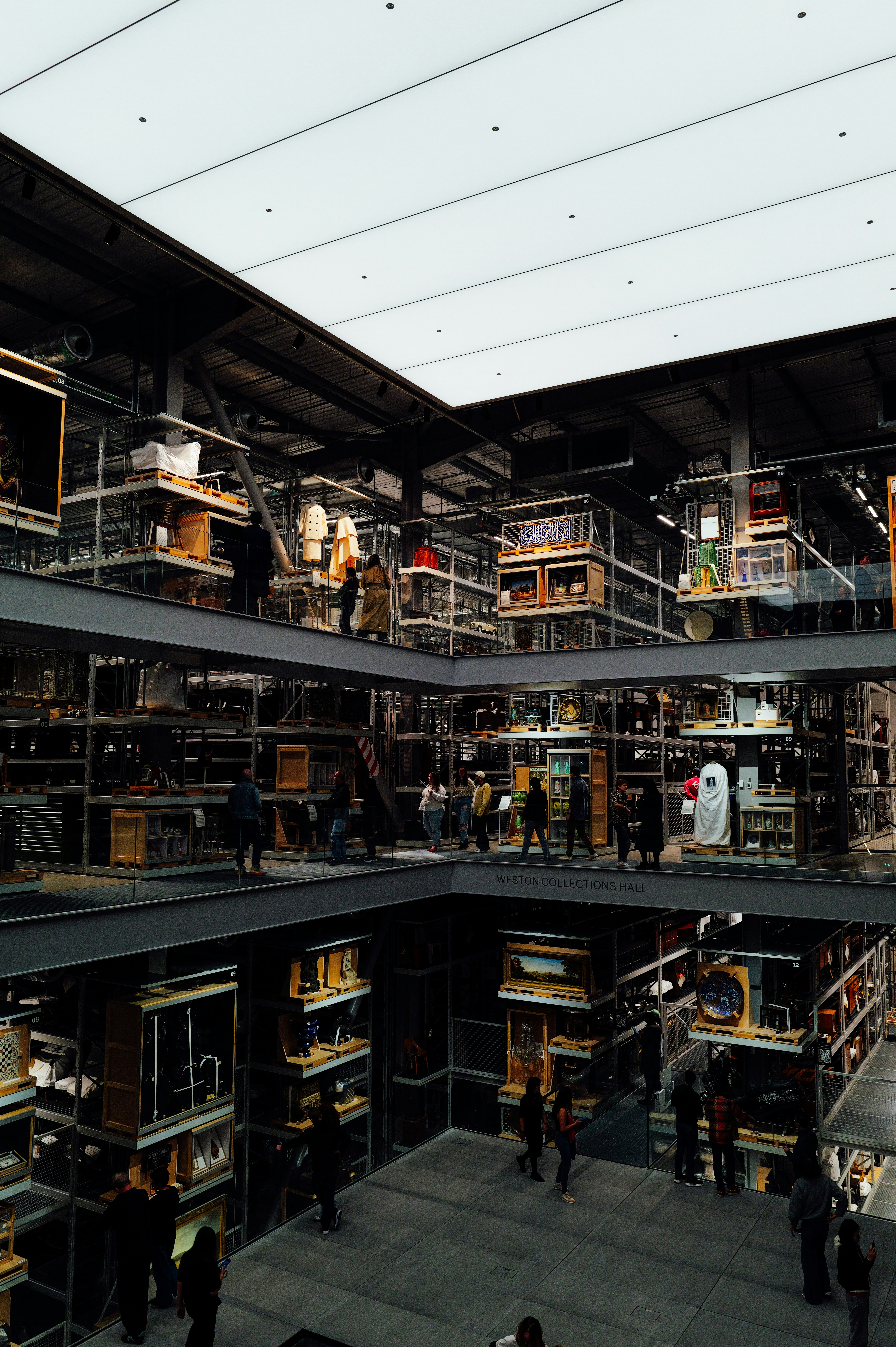 People explore a multi-level museum exhibit with shelves.