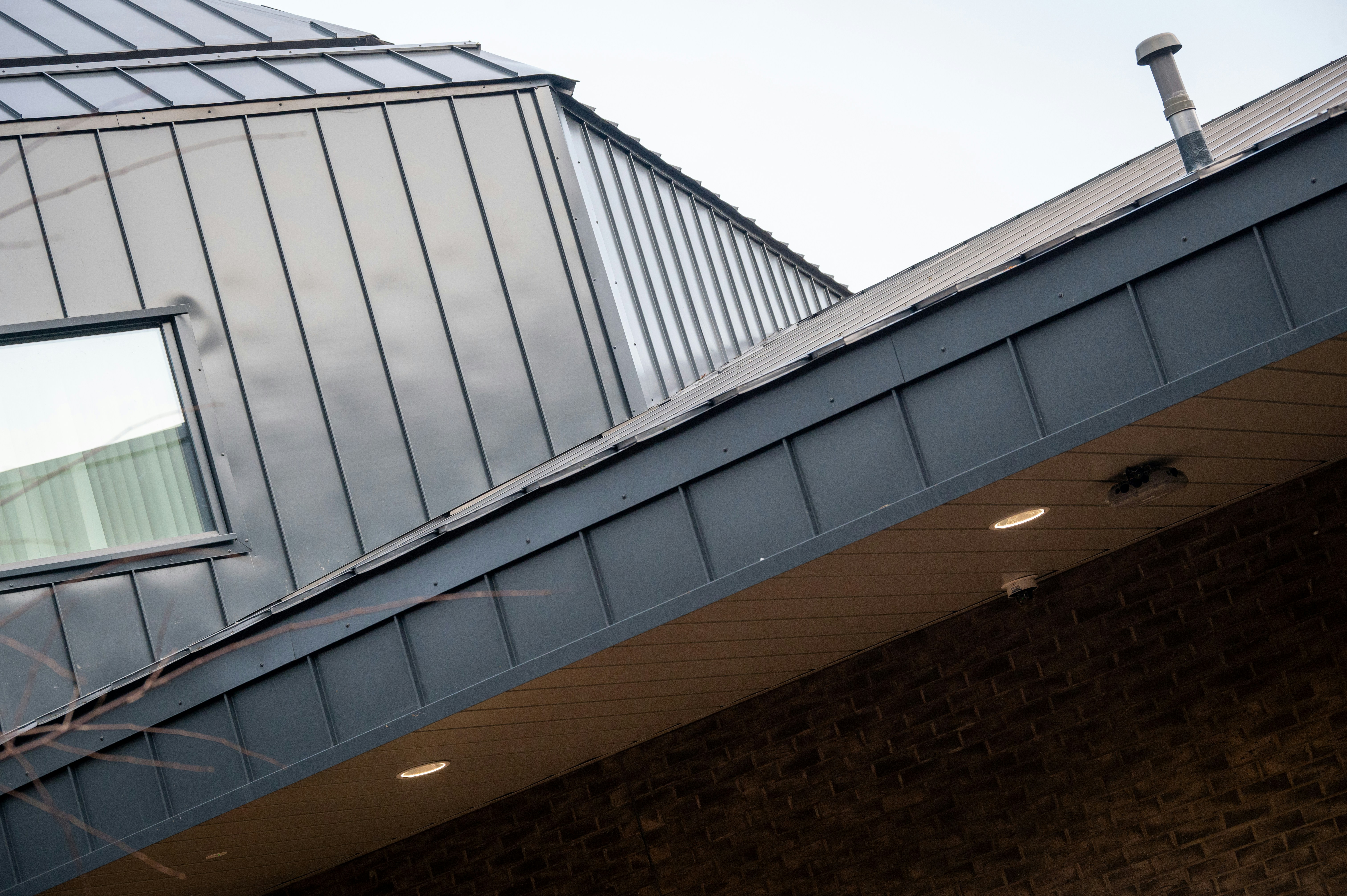 Modern building with metal roof and brick facade.