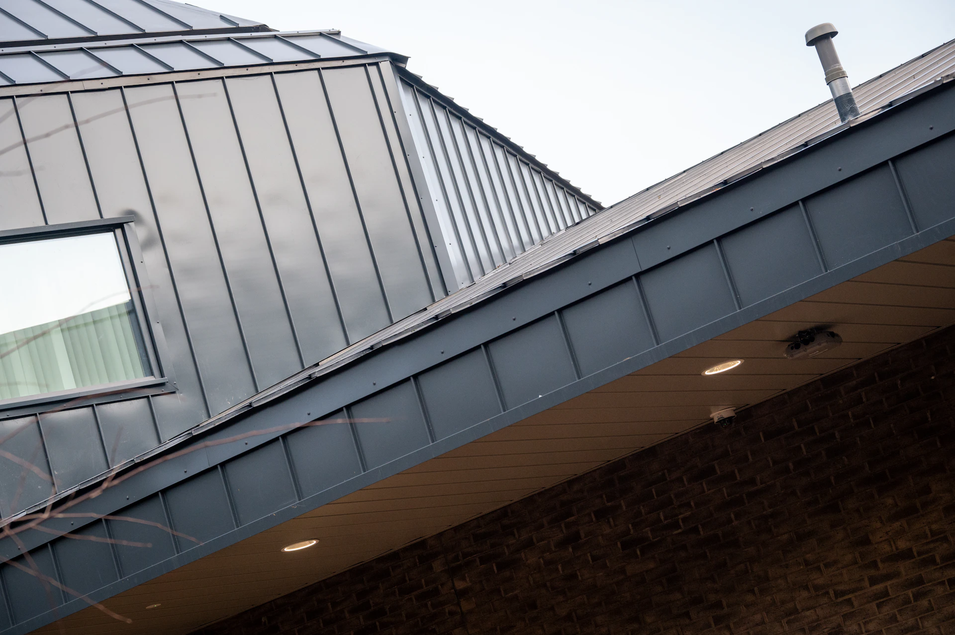 Modern building with metal roof and brick facade.