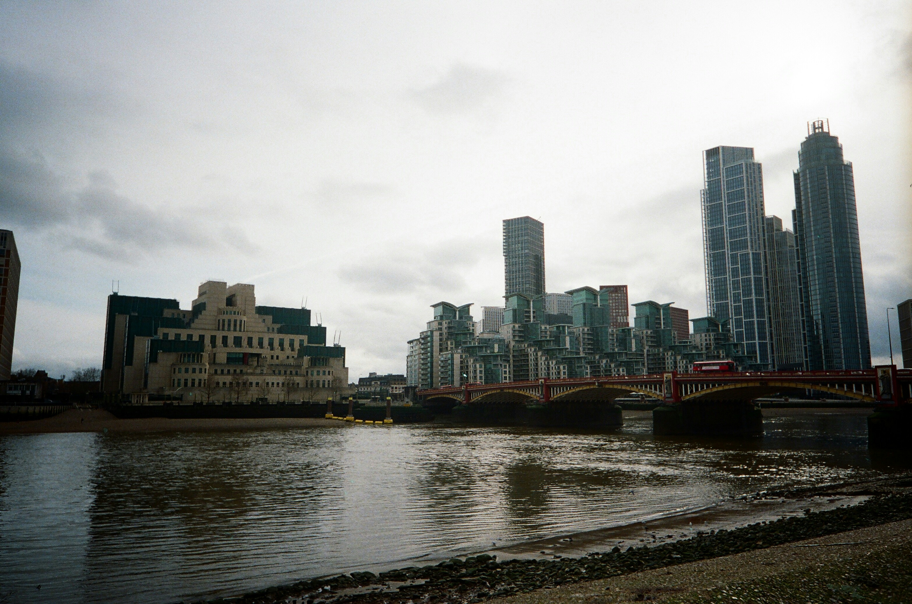 City skyline with river and bridge under cloudy sky