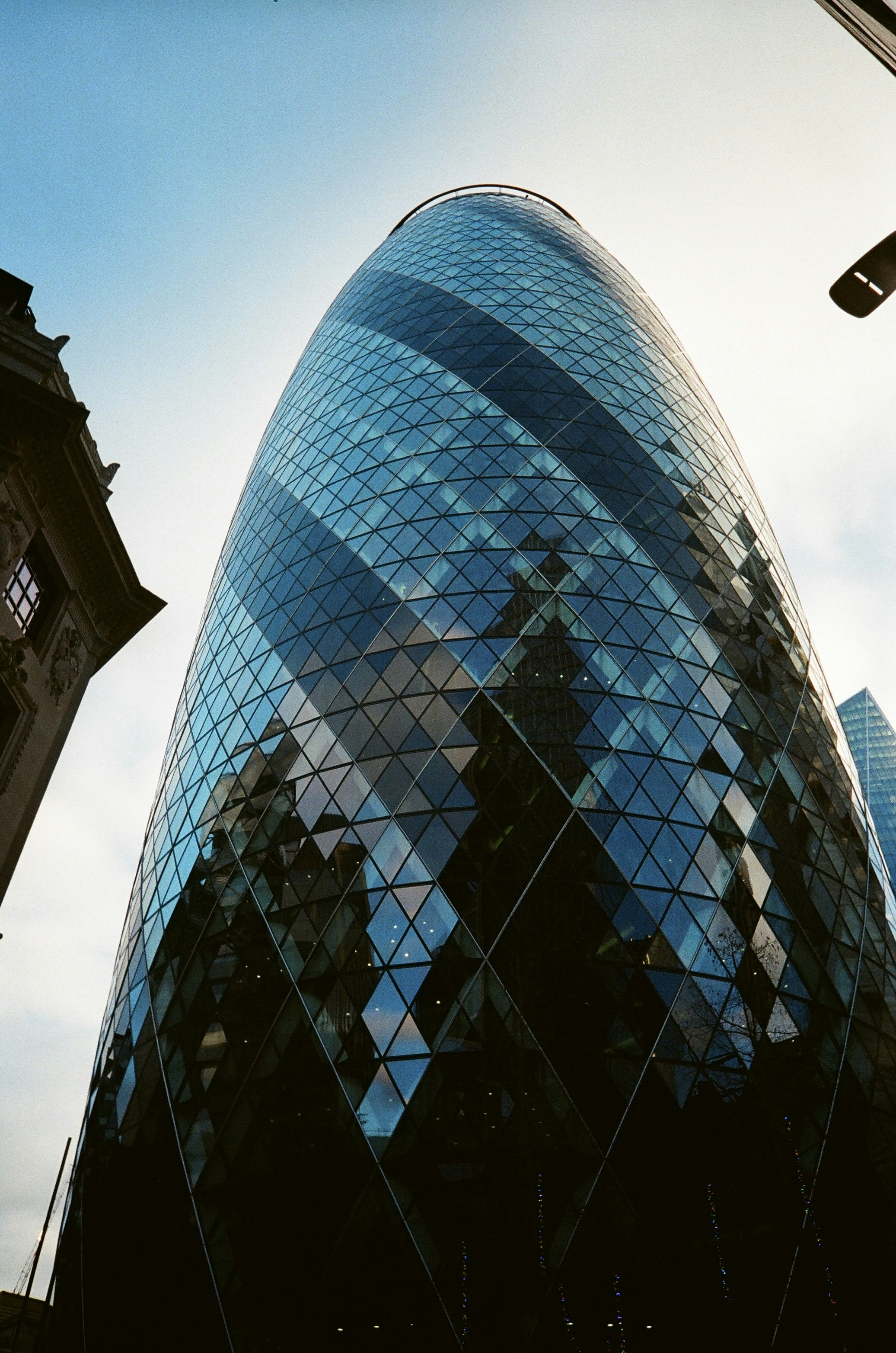 The gherkin building in london reflects the sky.
