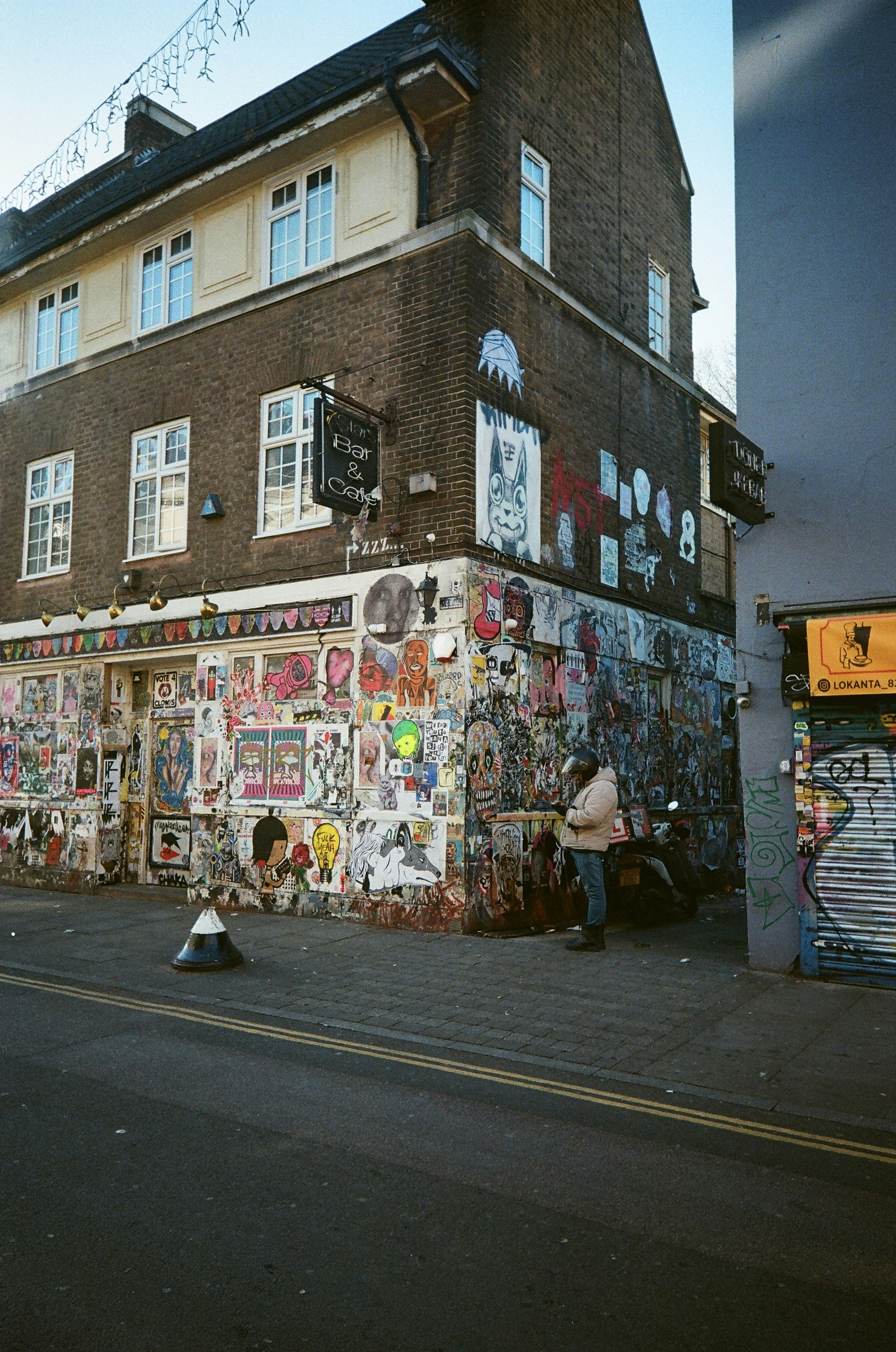 Building covered in artwork with a person standing outside.