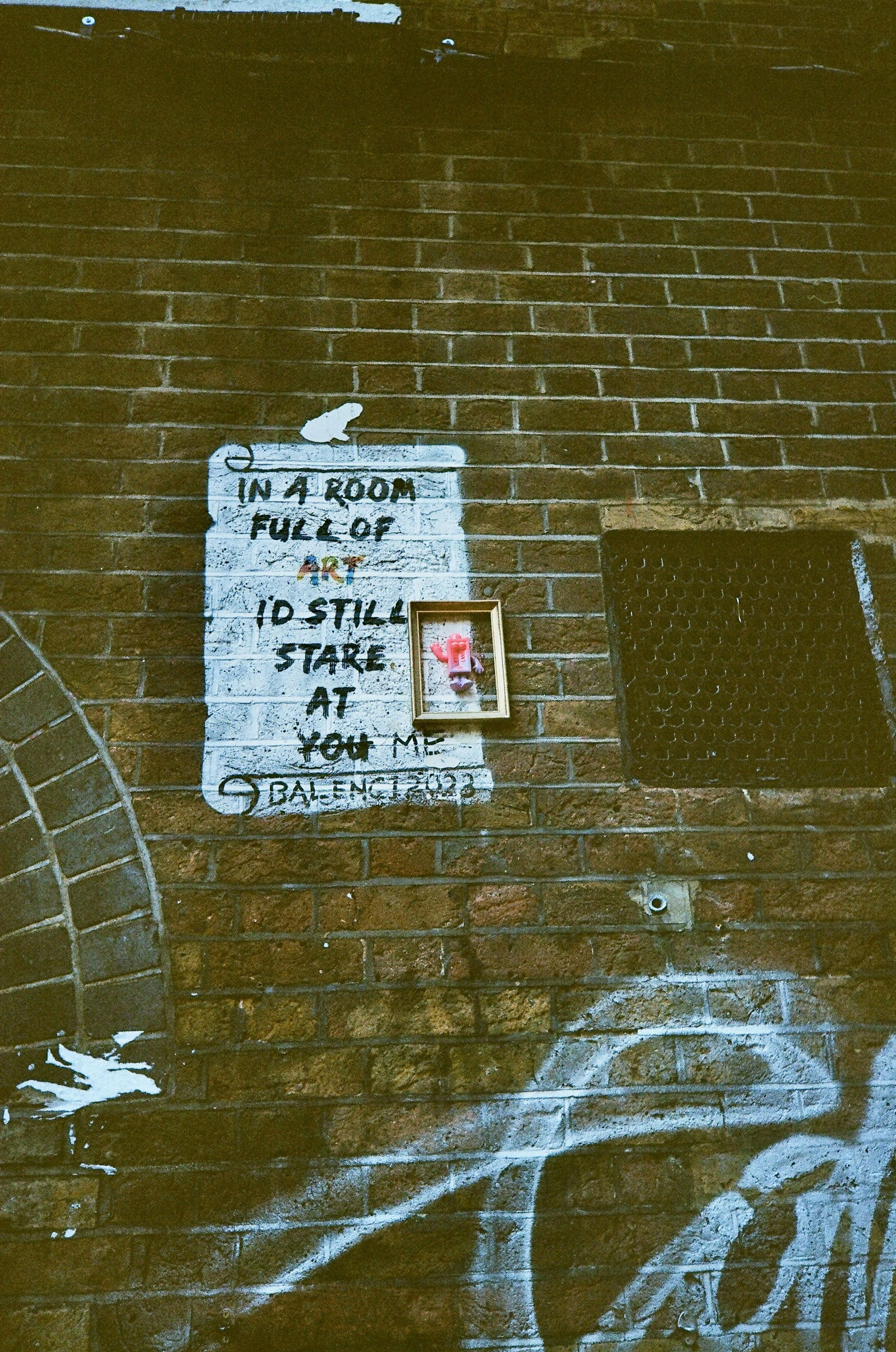 Graffiti art on a brick wall with a framed picture