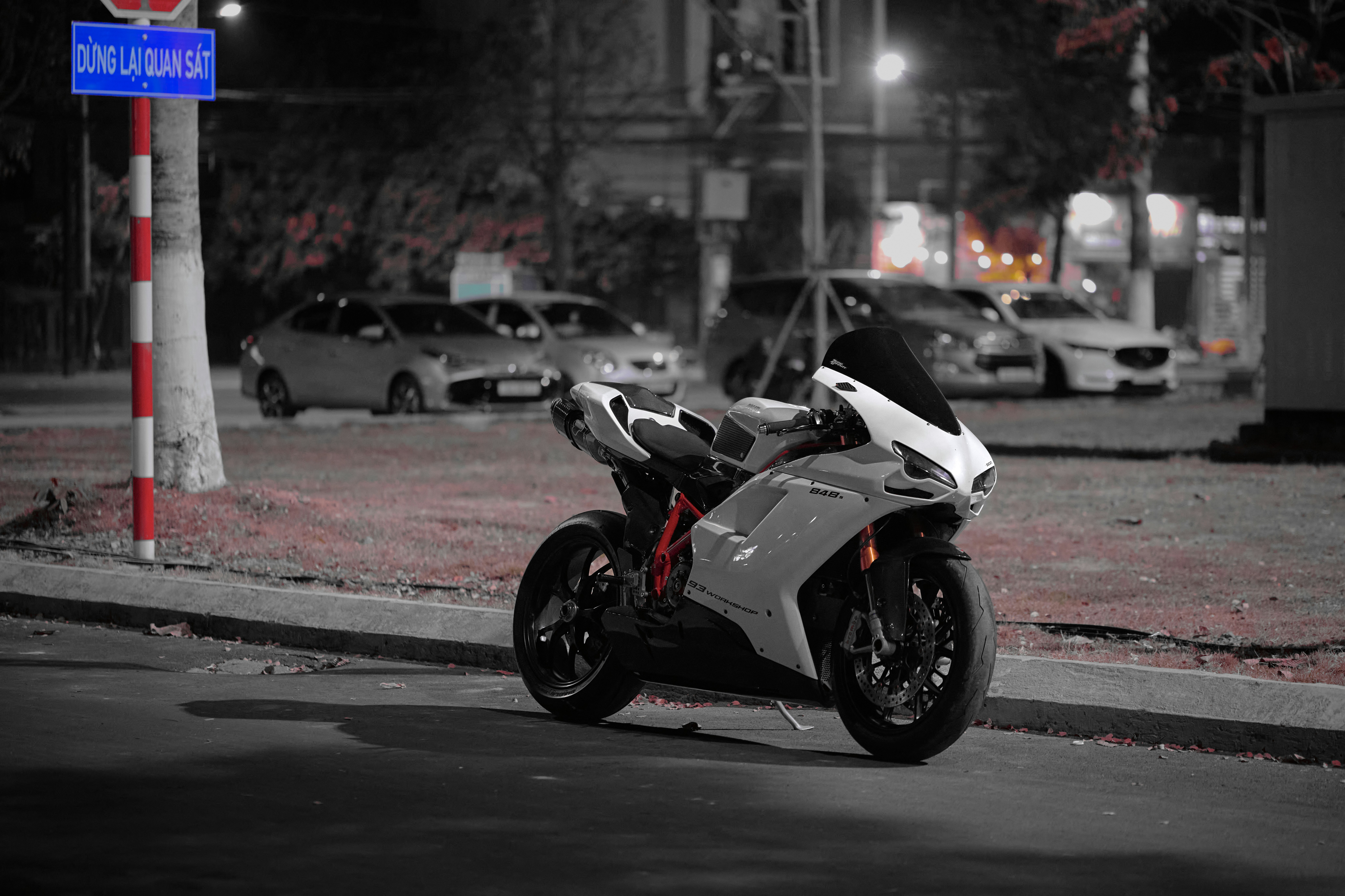 White sport motorcycle parked on a city street at night.