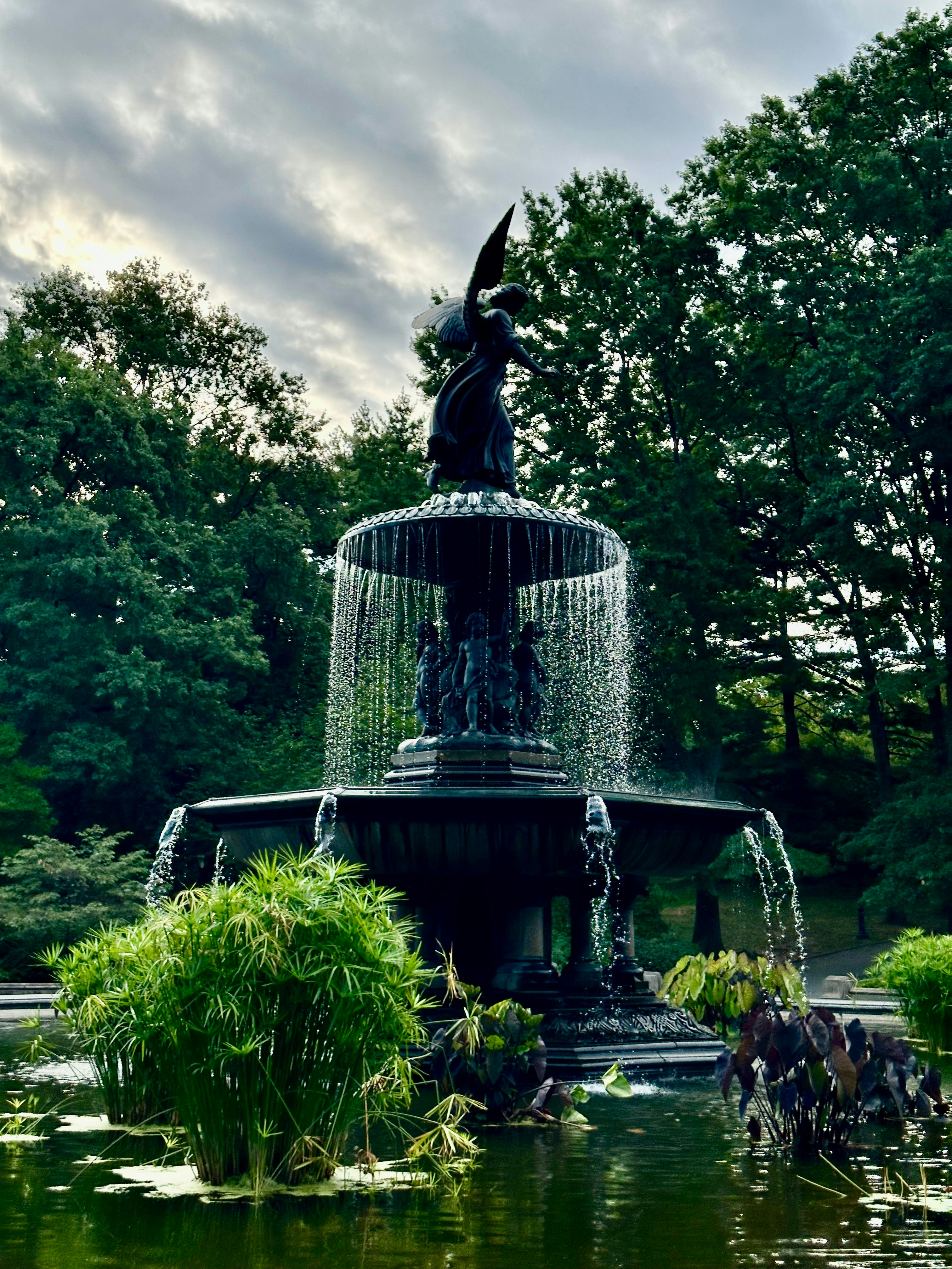 A grand fountain with cascading water surrounded by lush greenery.