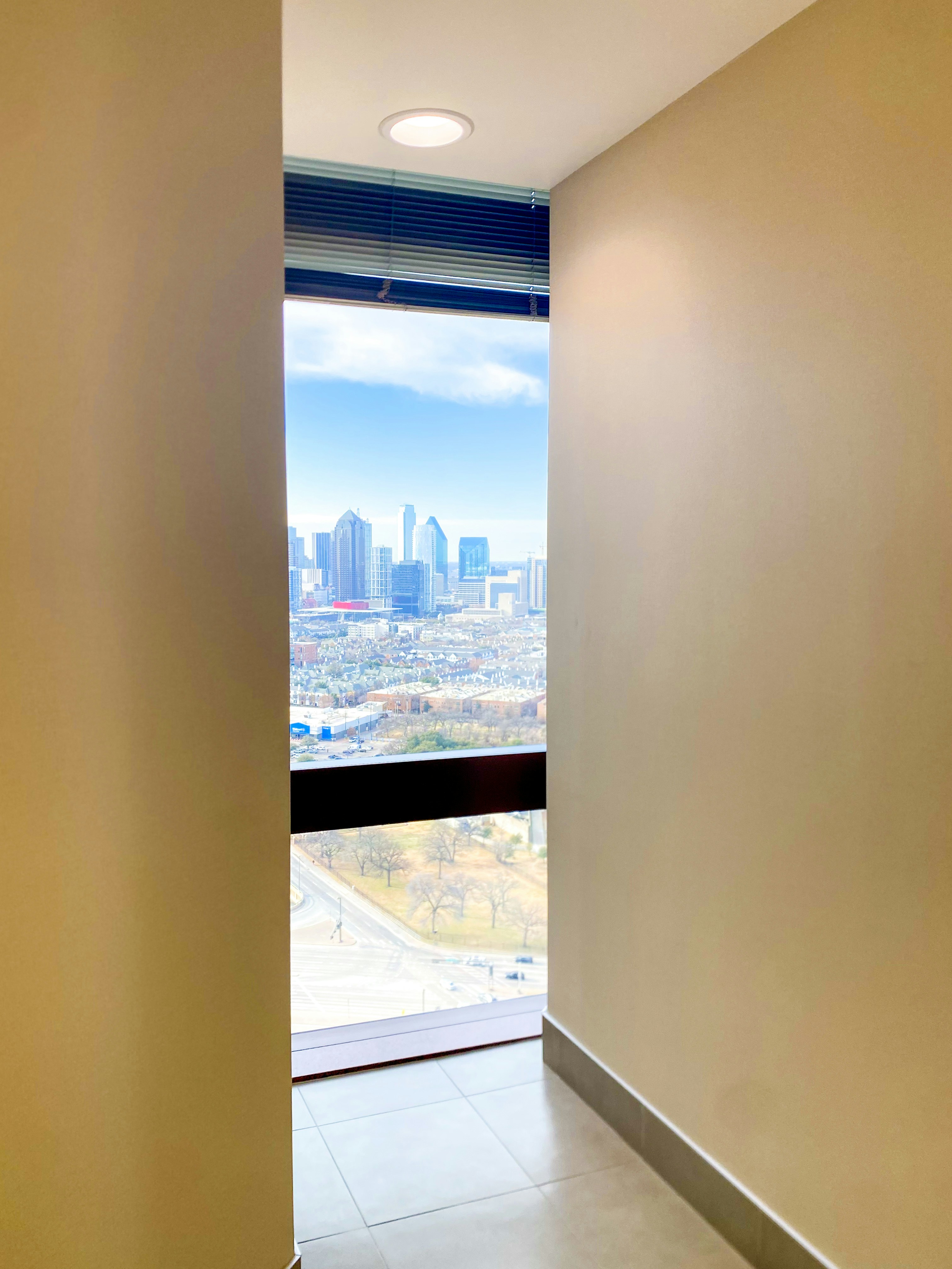 View of a cityscape through a narrow hallway window.