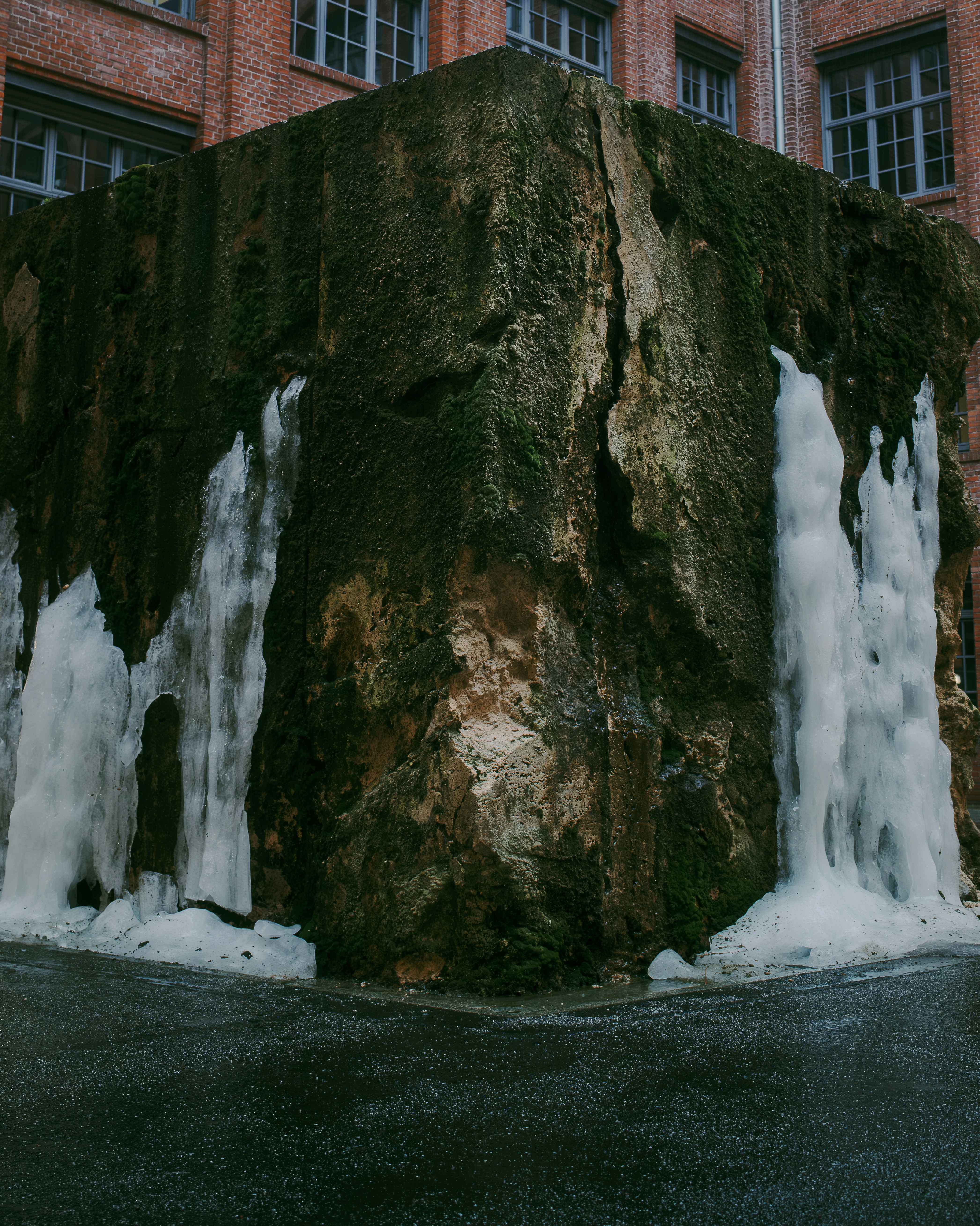 Ice formations on a moss-covered concrete structure