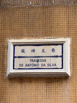 Street sign with chinese characters and portuguese text.
