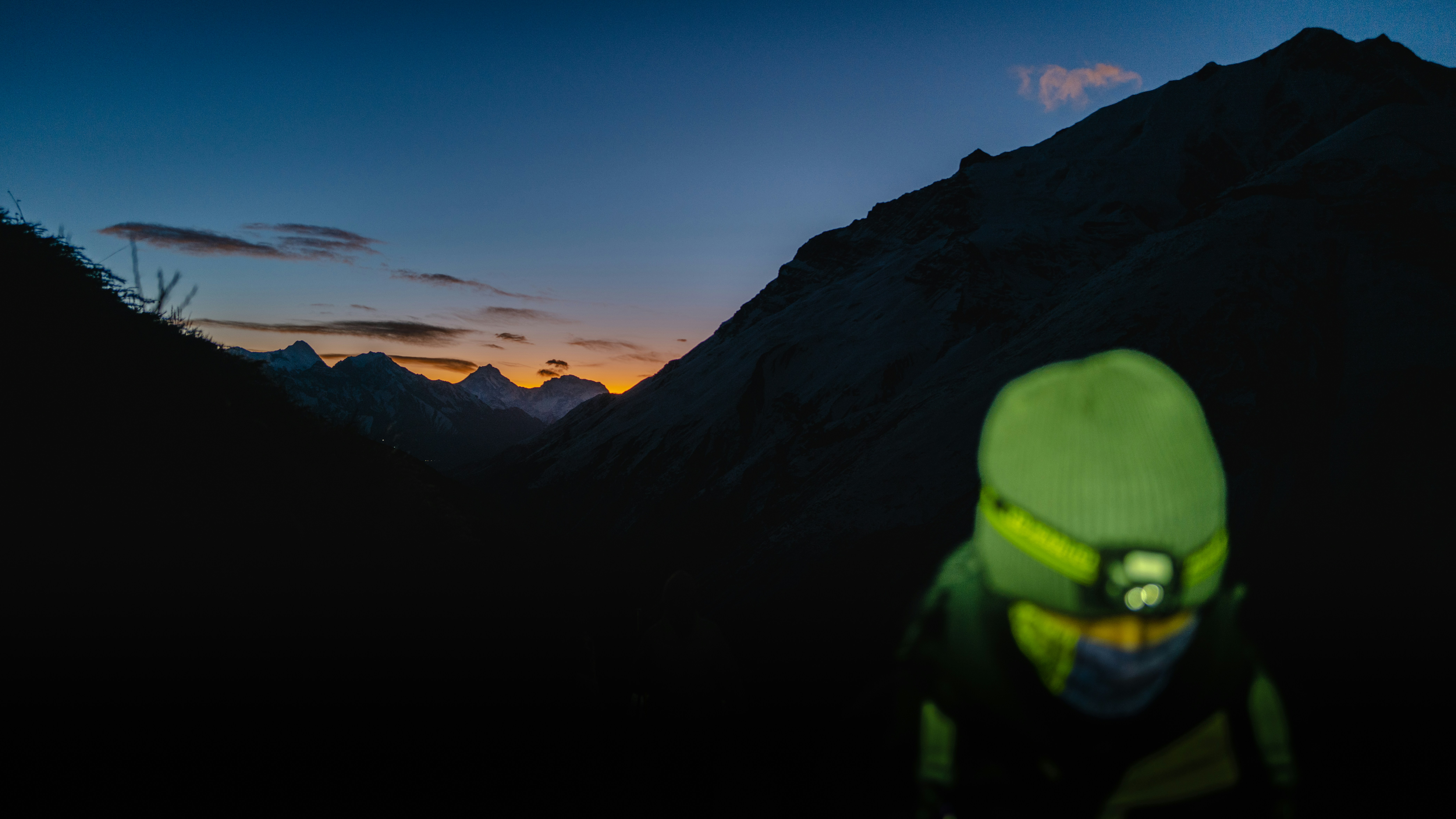 Person wearing headlamp at dusk in mountains