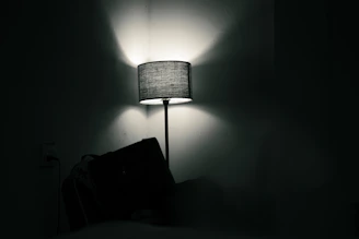 A lamp illuminates a dark room with shadows