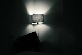 A lamp illuminates a dark room with shadows