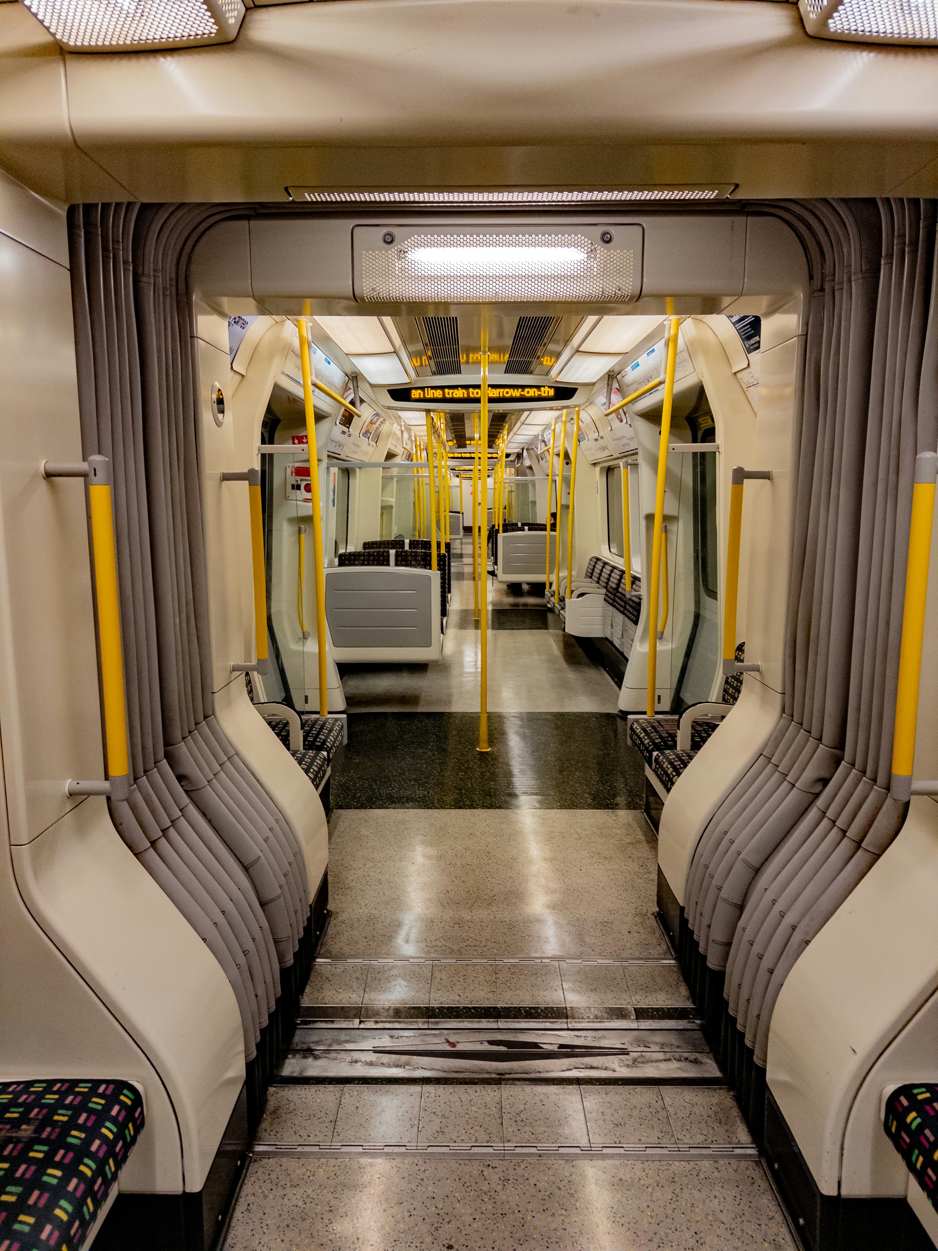 Interior of an empty subway train carriage with yellow poles.