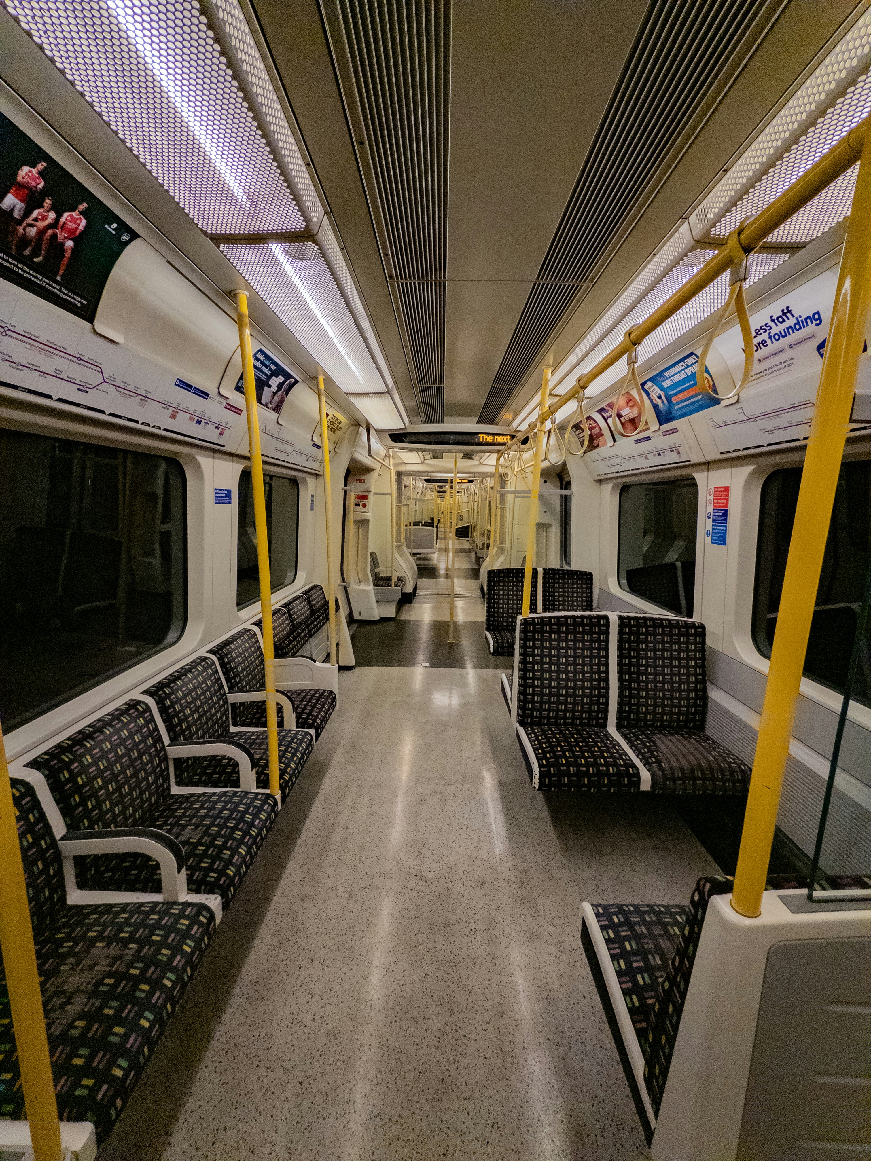 Empty train carriage with patterned seats and yellow poles