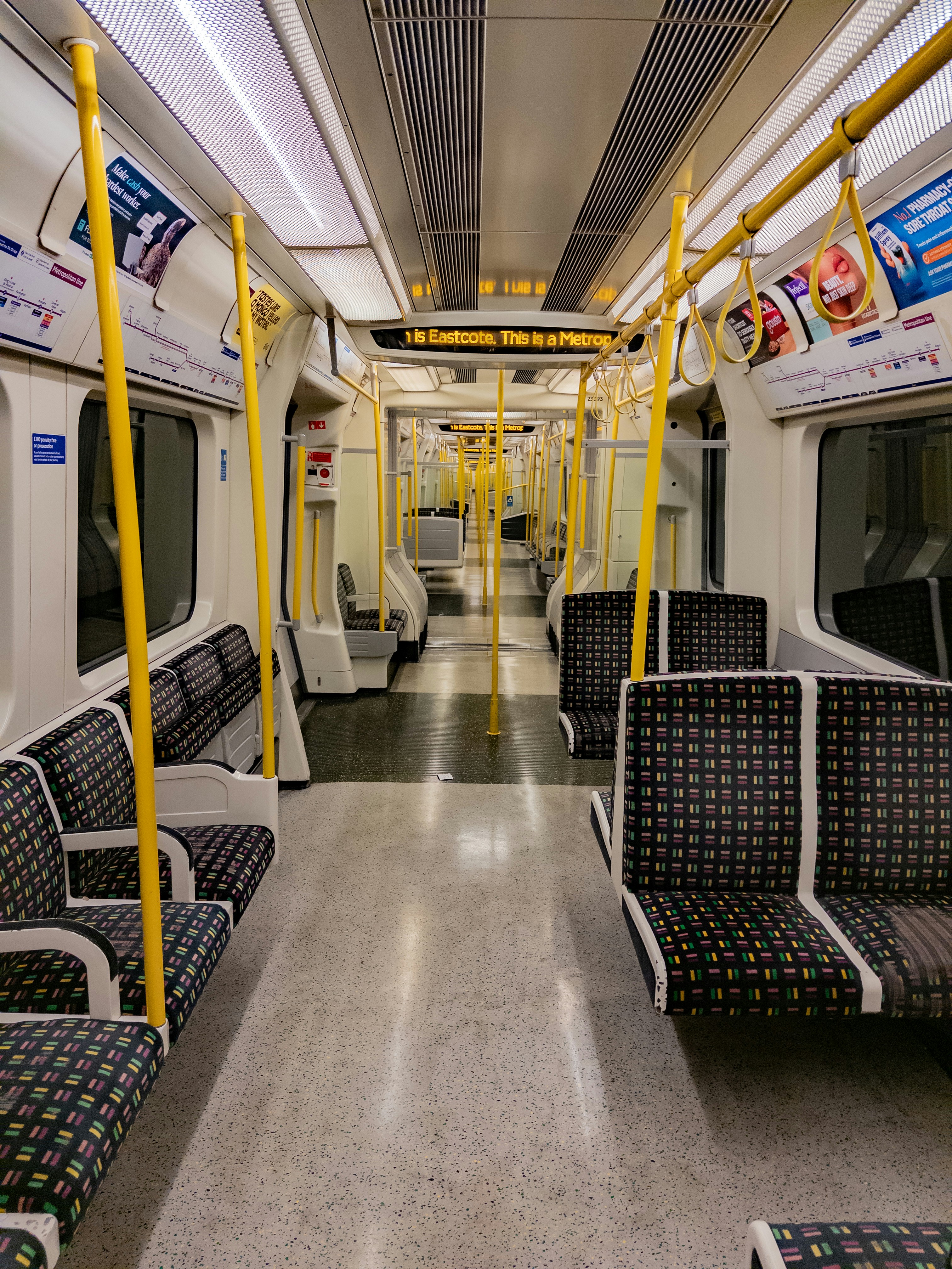 Interior of an empty subway train with yellow poles.
