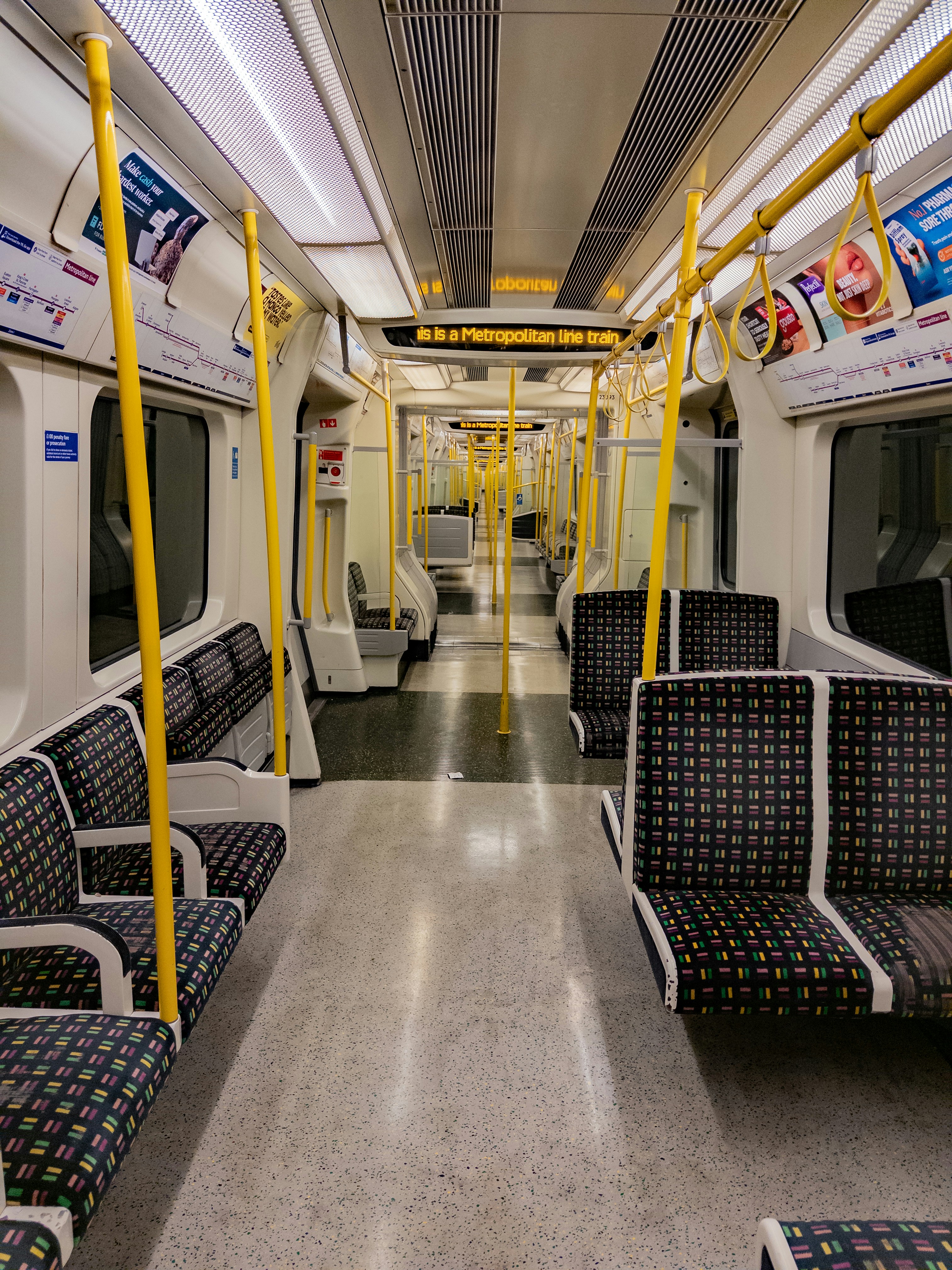 Interior of an empty subway train with yellow poles.