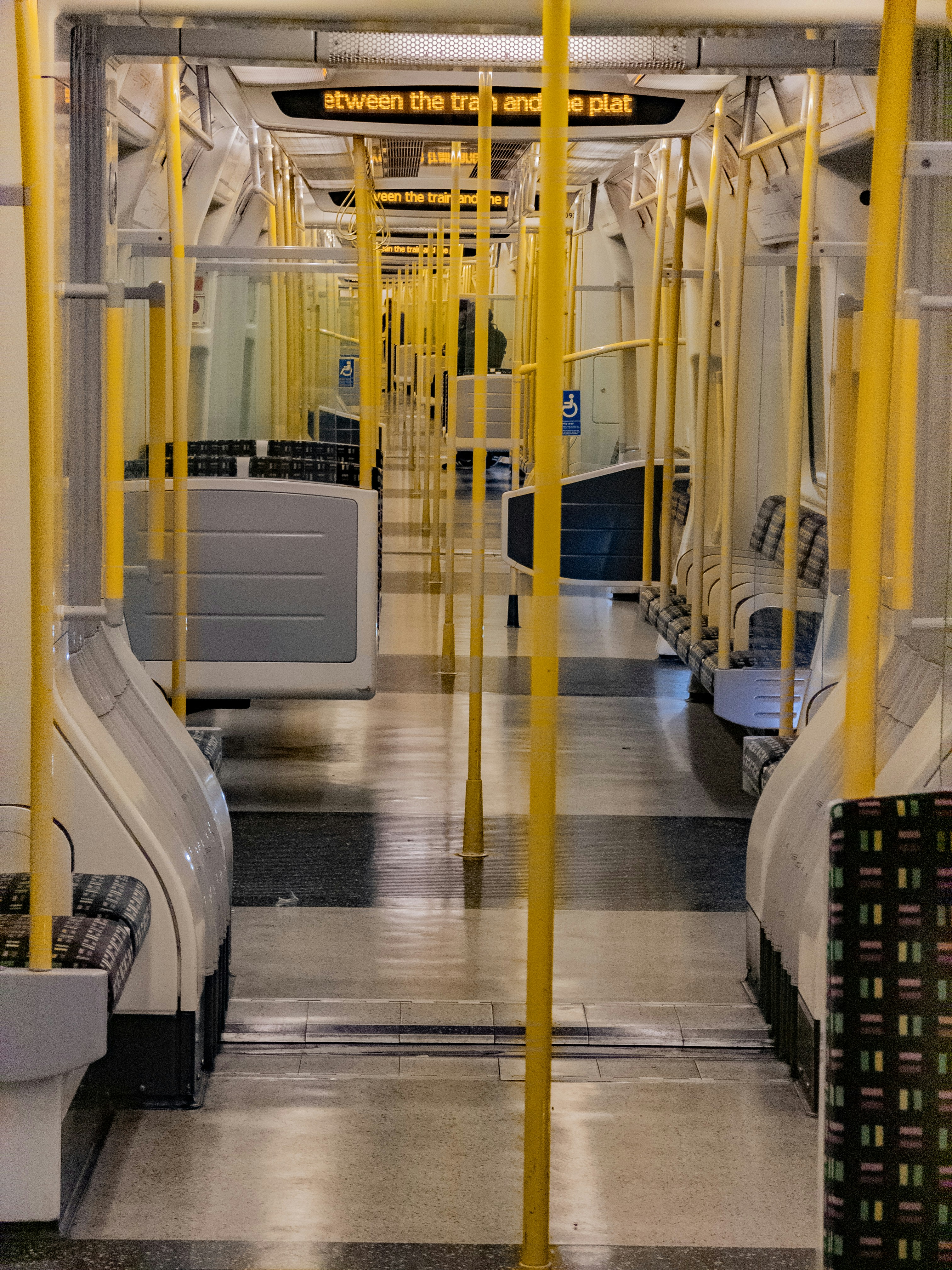 Interior of an empty subway train with yellow poles.