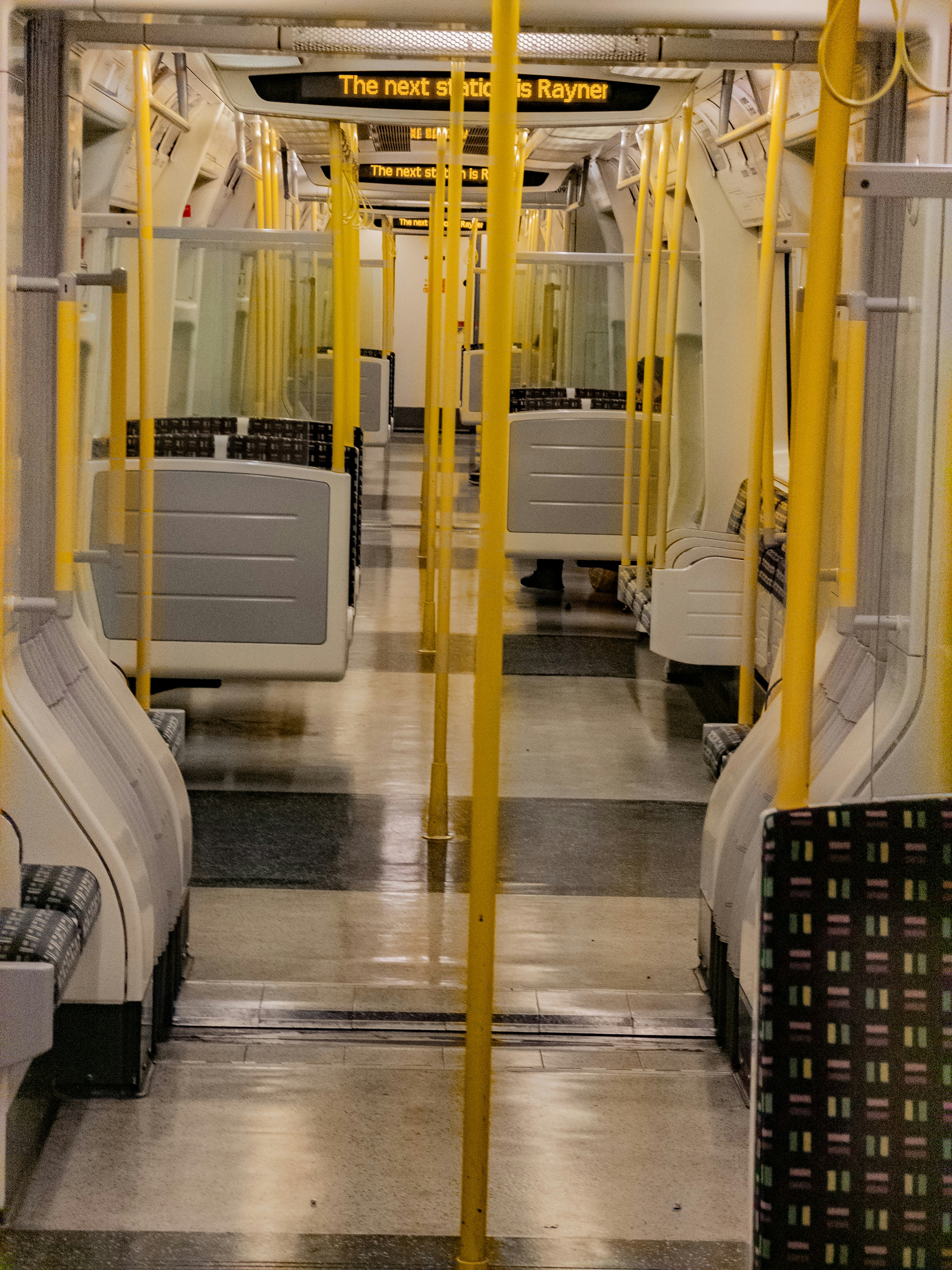 Empty subway train interior with yellow poles and seats
