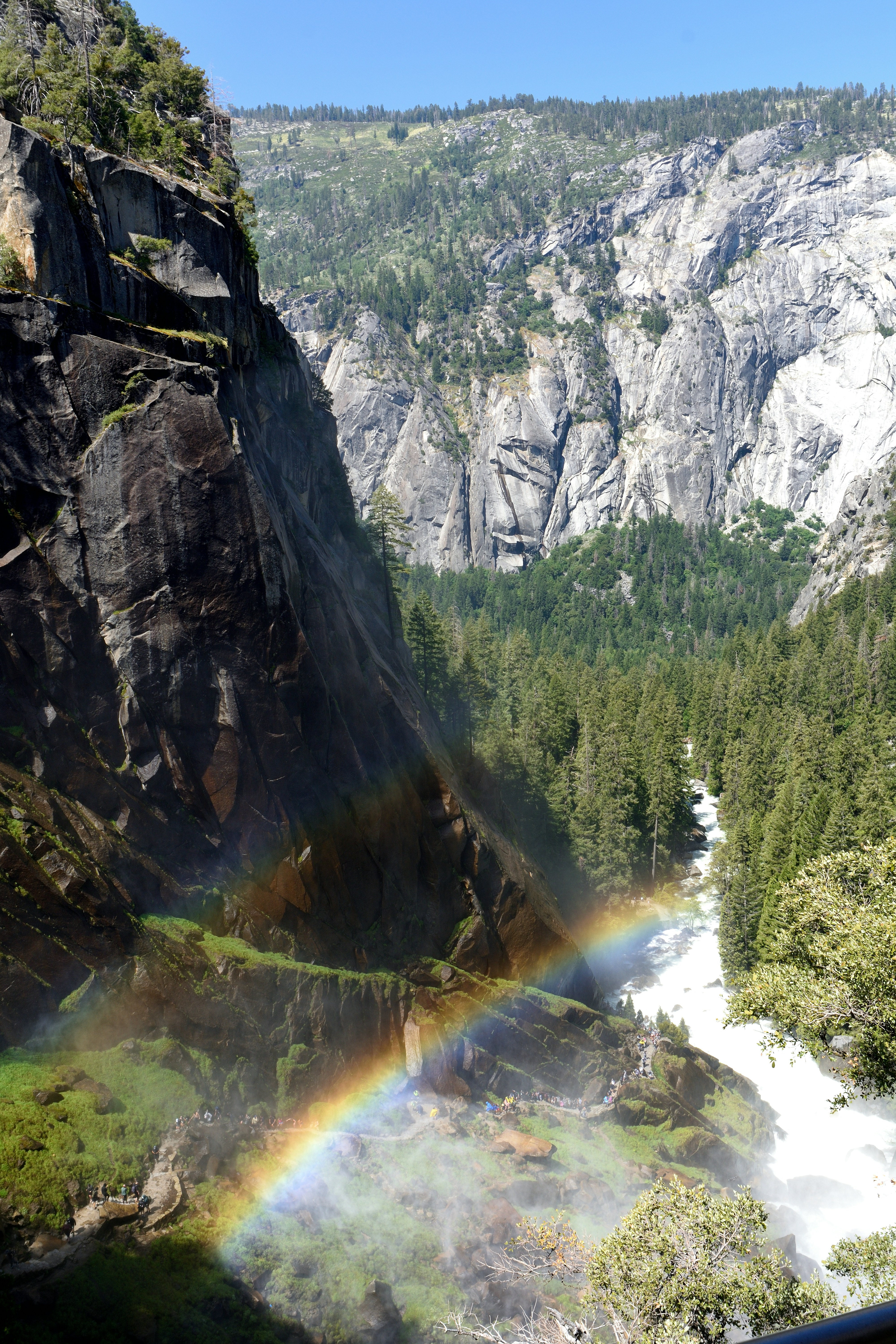 Waterfall creates a rainbow in a rocky mountain forest.