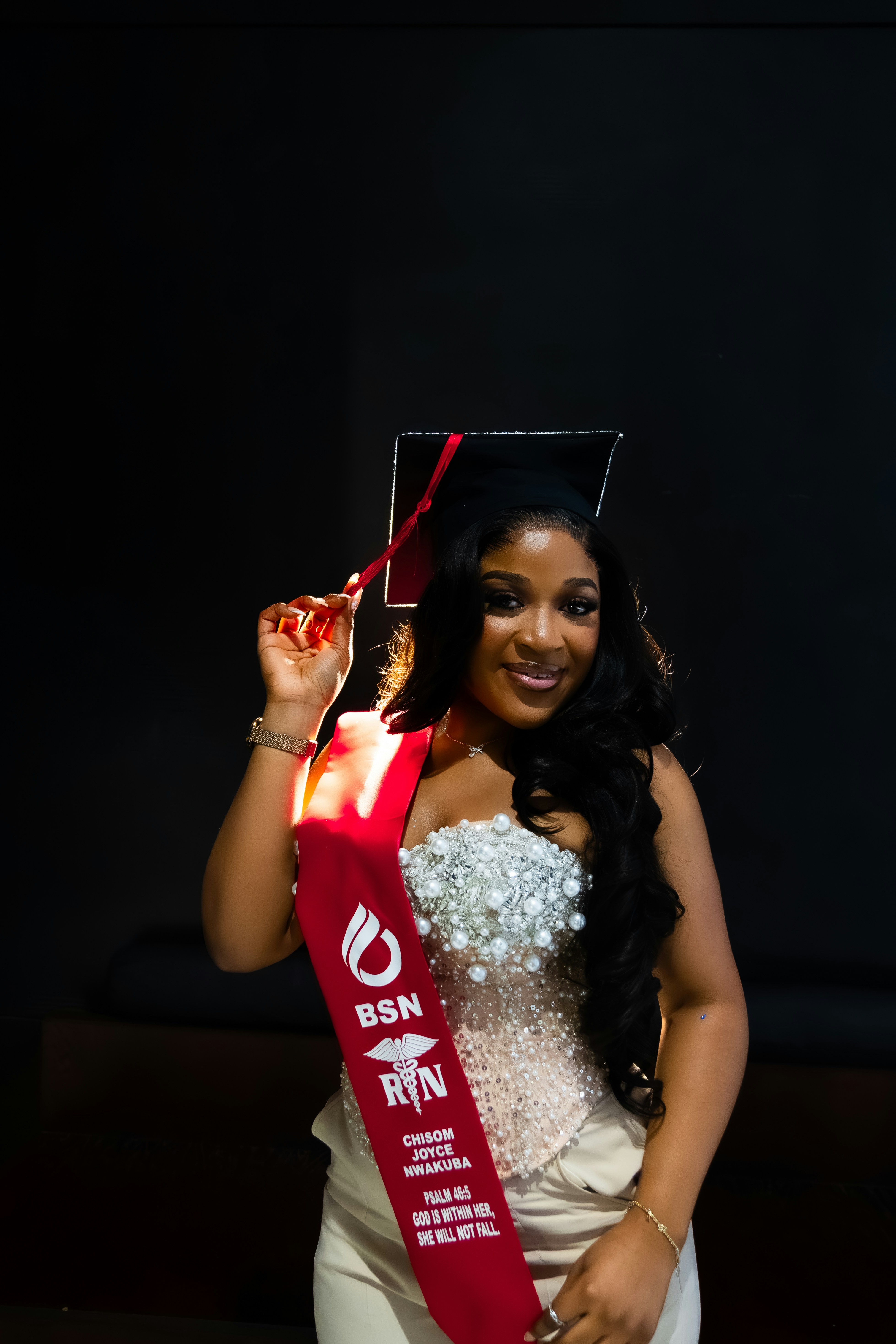 A confident nursing graduate poses proudly in a studio, wearing a graduation cap and a BSN RN sash. The portrait highlights achievement, dedication, and the powerful moment of completing a nursing journey, symbolizing resilience, success, and the beginning of a professional career in healthcare.