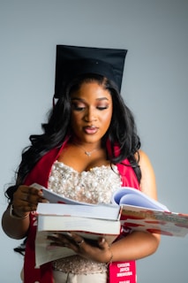 A graduate in cap and gown holds books