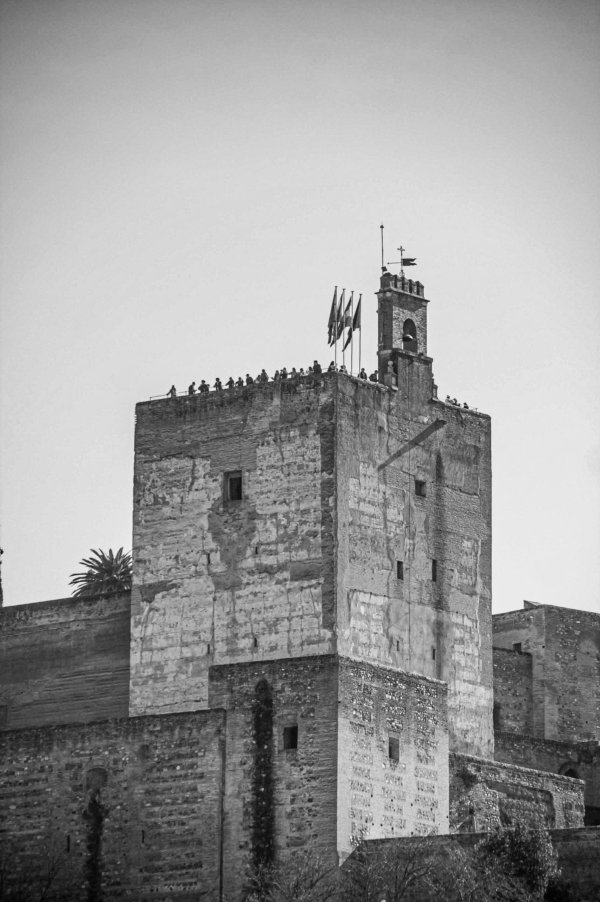 Ancient stone fortress with flags atop tower.
