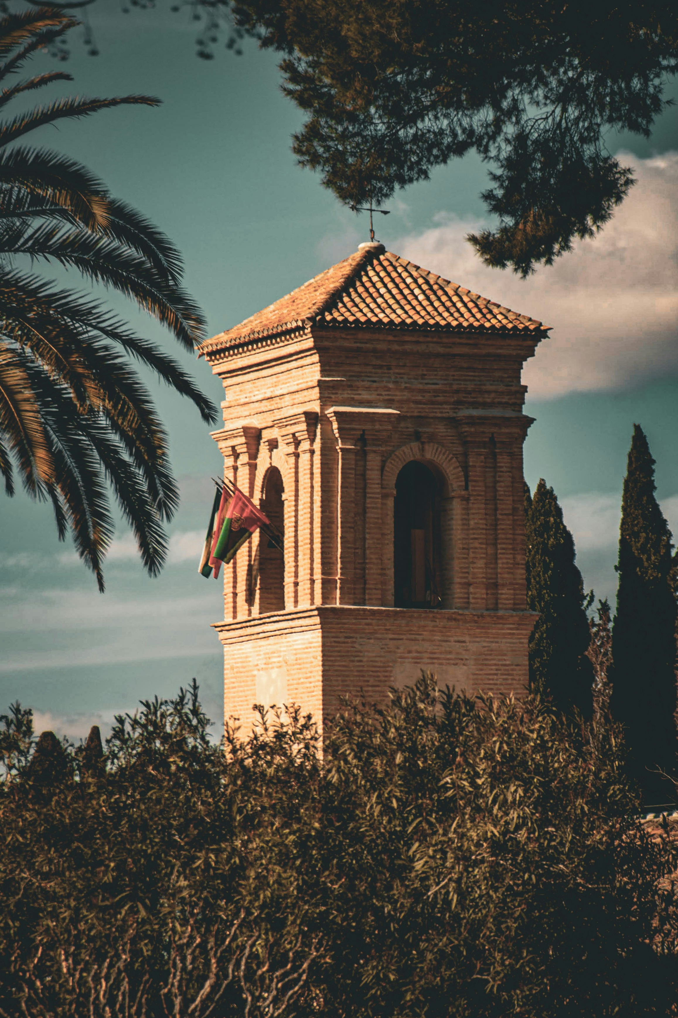 Brick tower with arched windows and a flag.