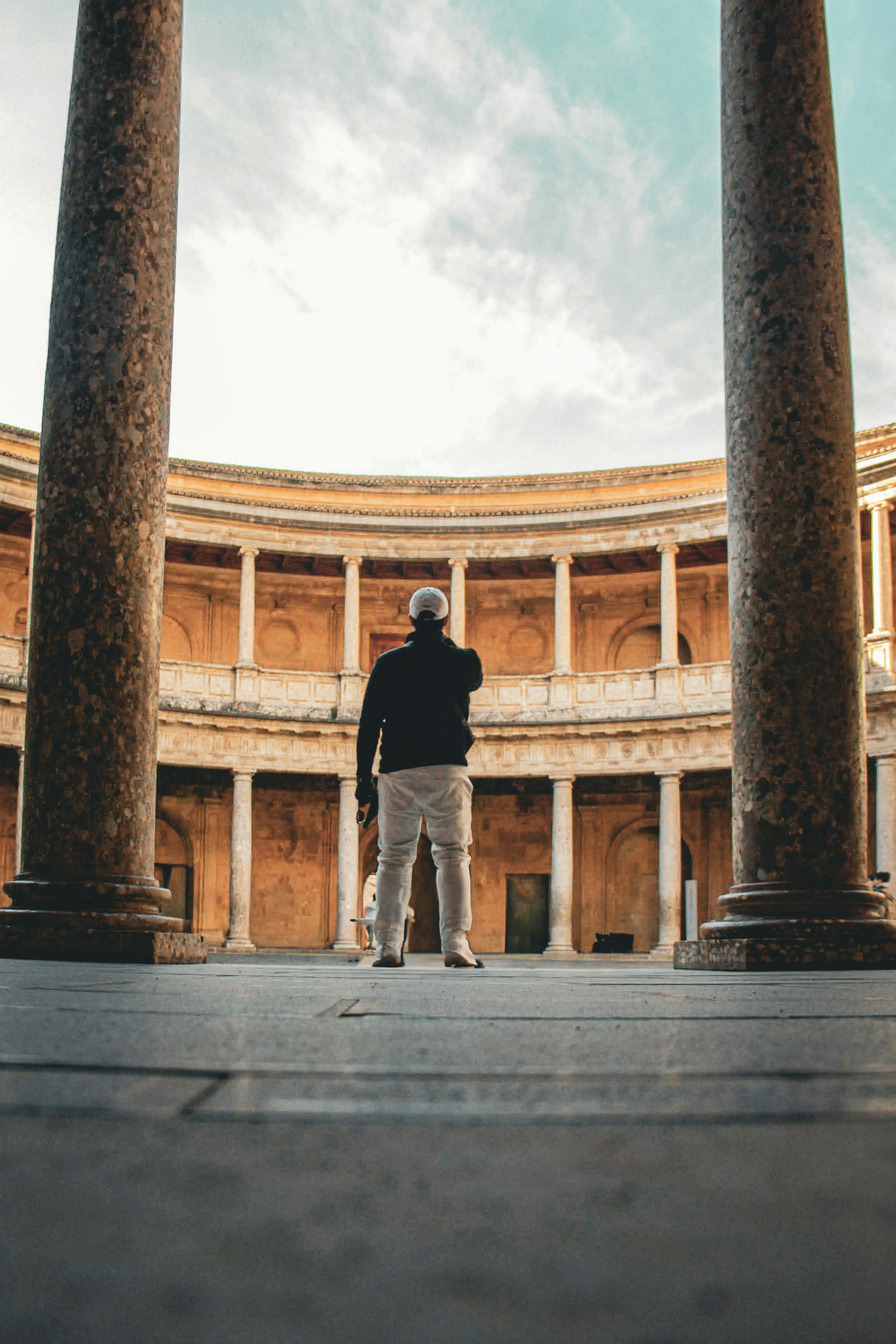 Man standing between columns in ancient courtyard