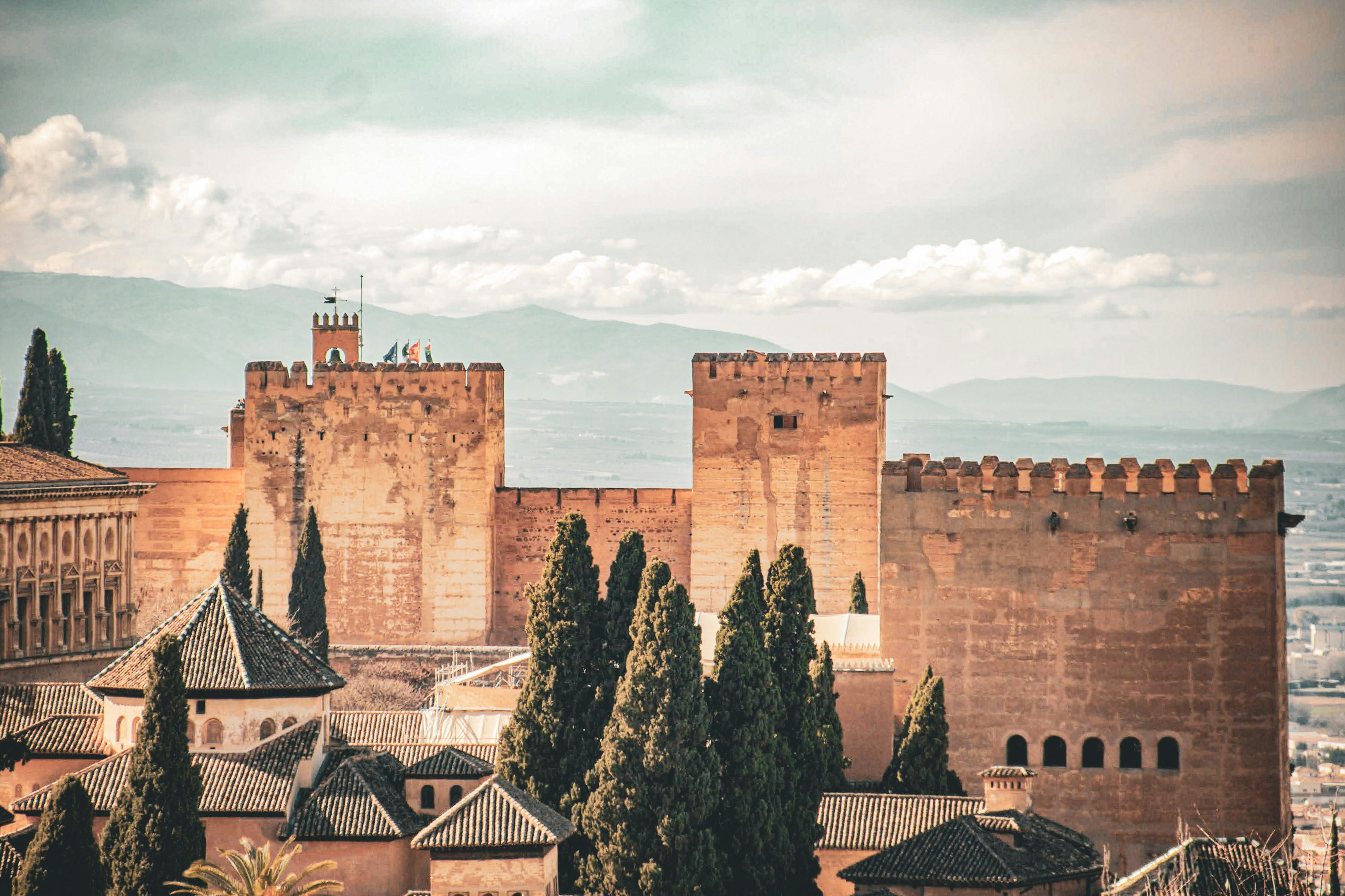 Ancient fortress with cypress trees and distant mountains.