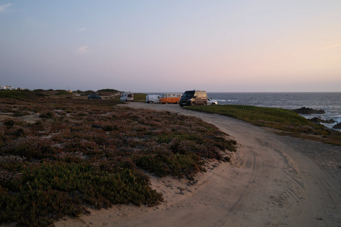 A simple wooden house being transported on a truck along a coastal road, part of a managed retreat program