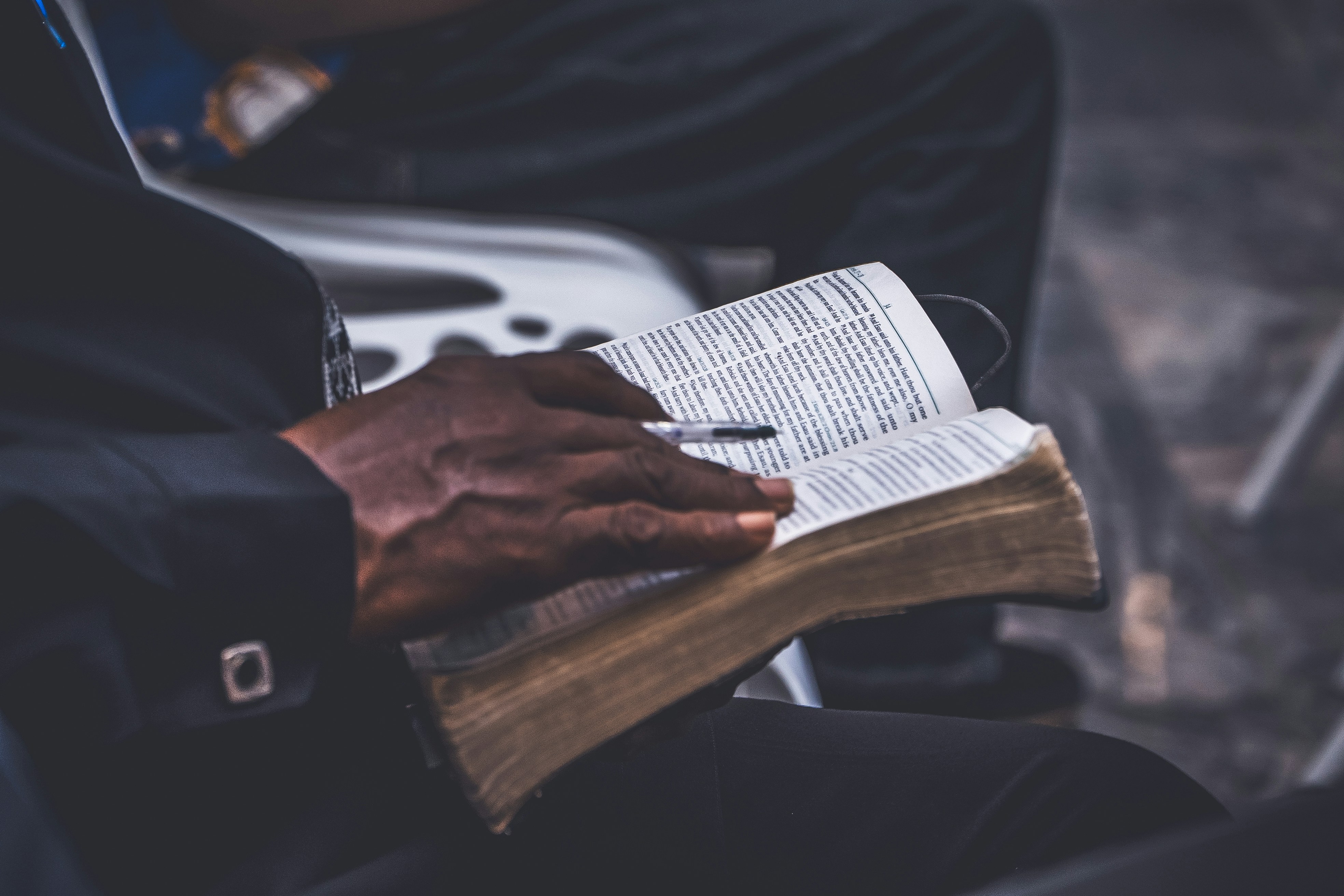 A person holding an open book with a pen.