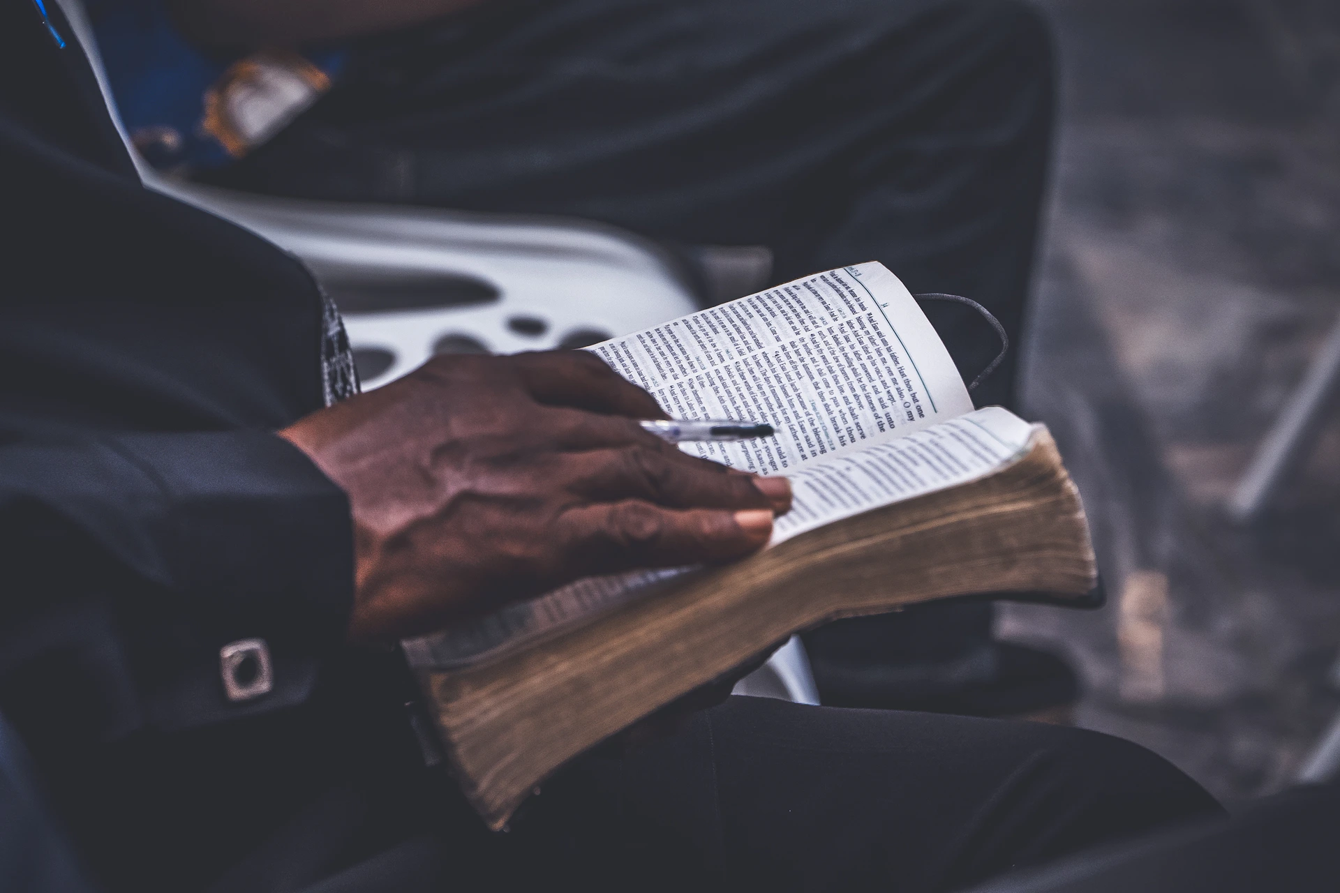 A person holding an open book with a pen.