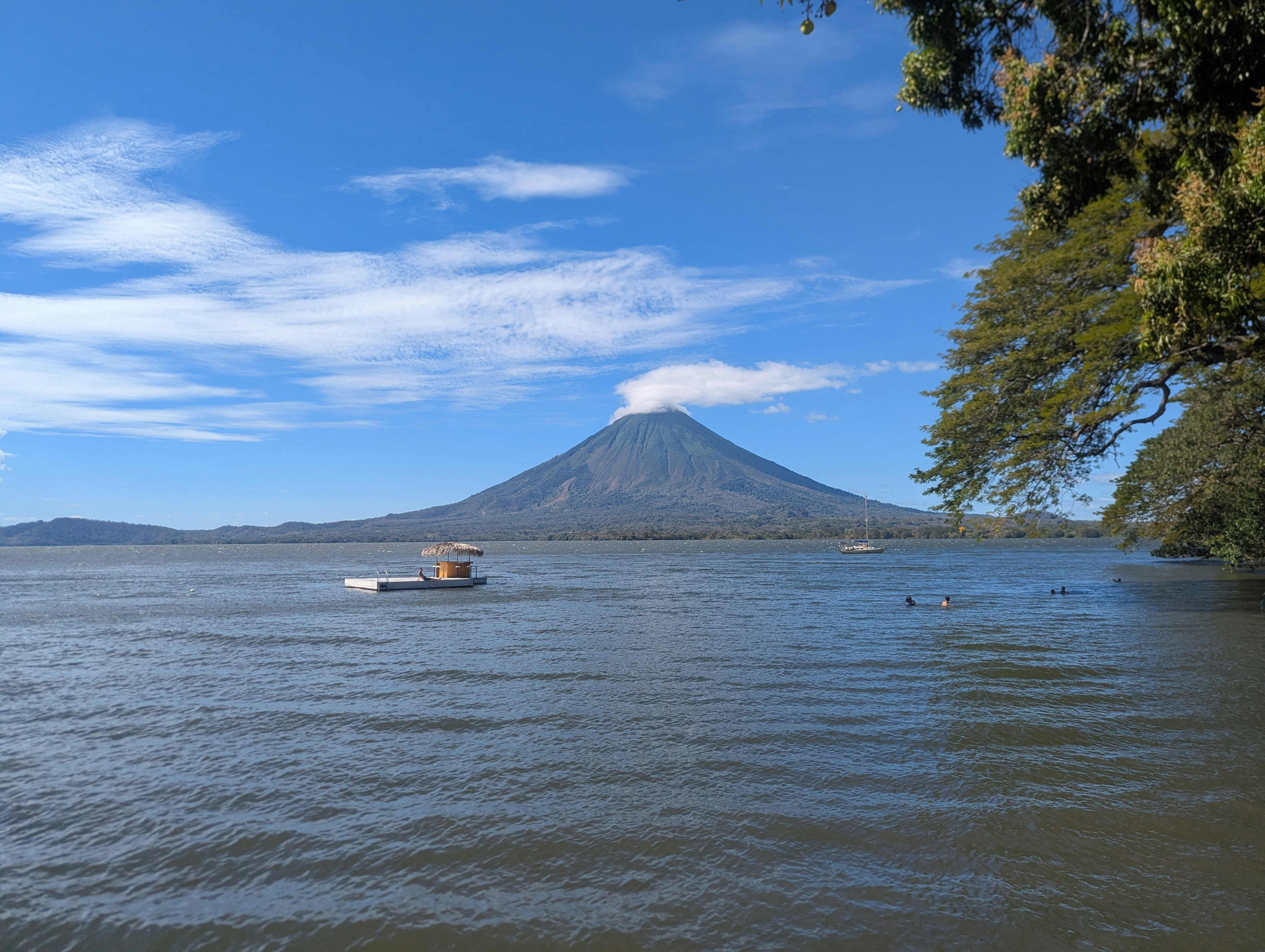 Volcano over a calm lake with a small boat.