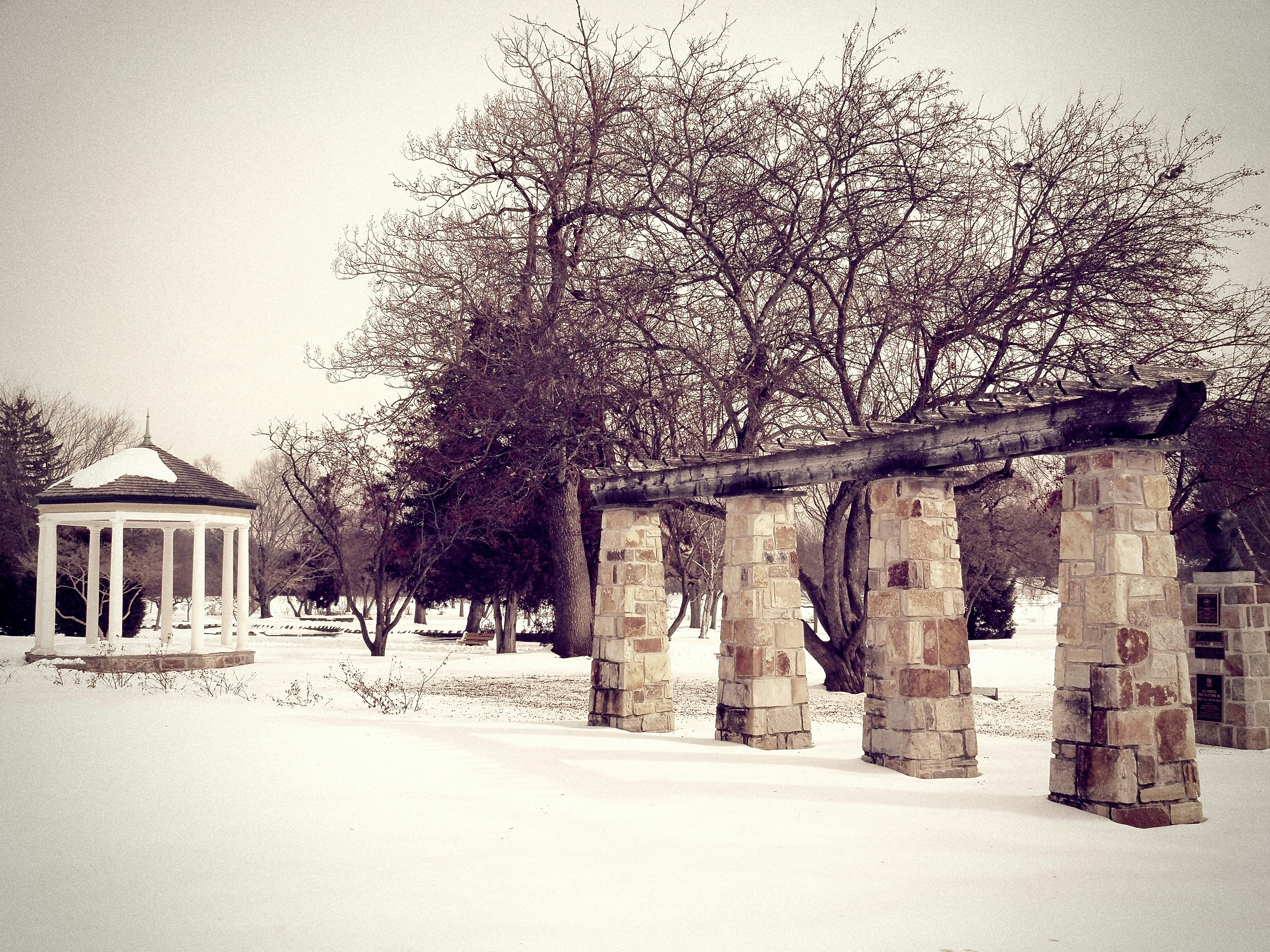 Snow covered park with gazebo and stone pillars