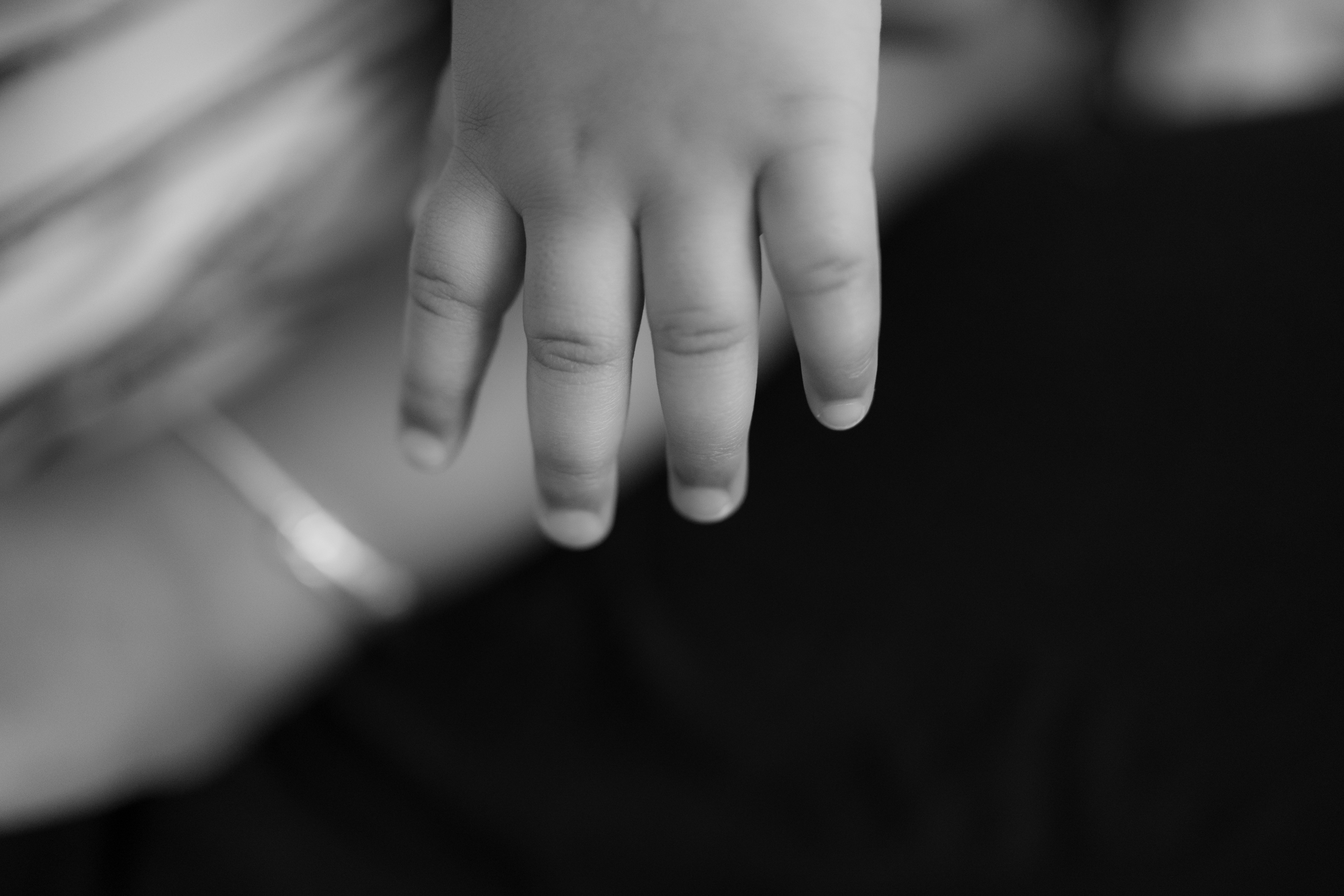 A close-up of a baby's hand reaching down.