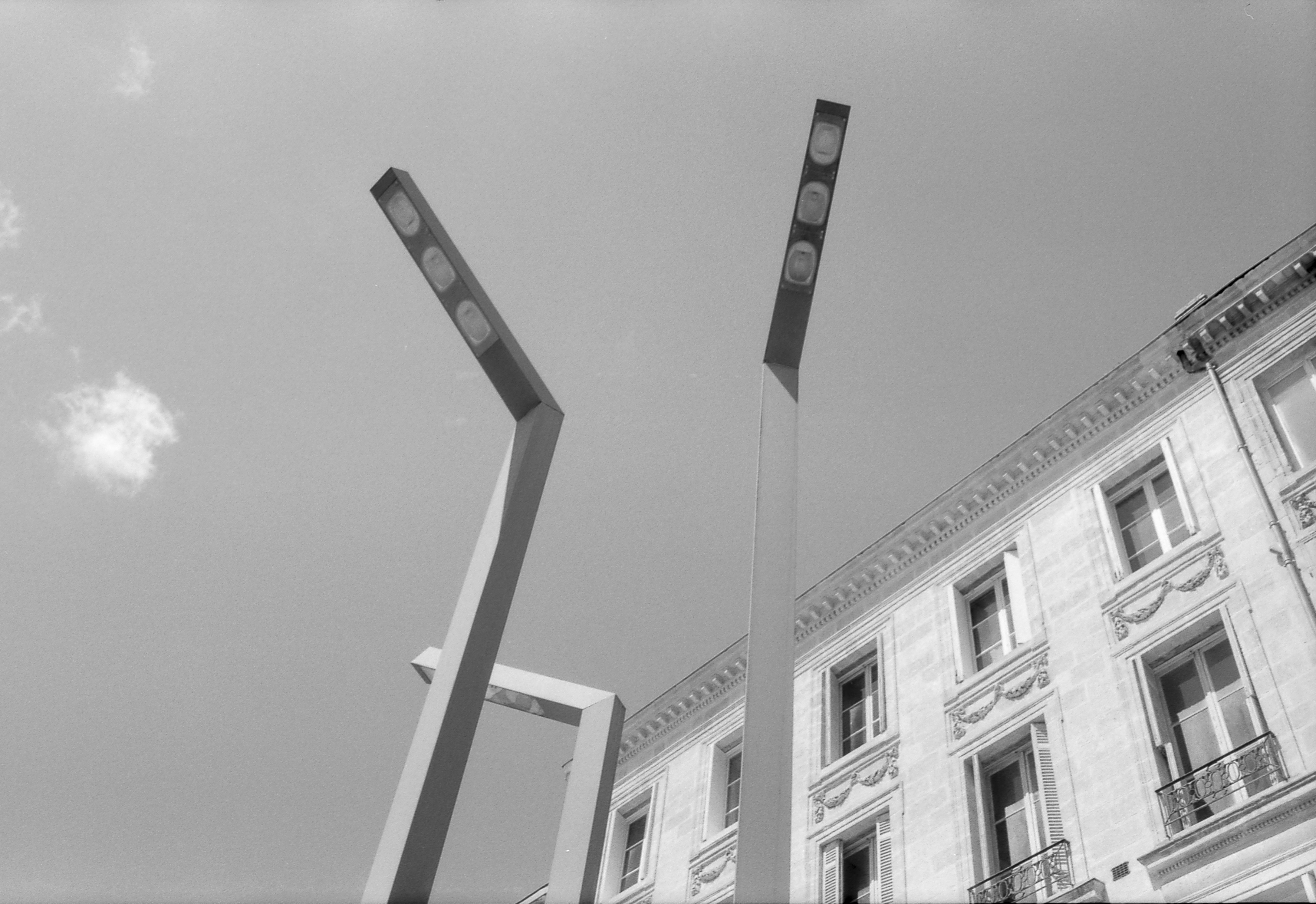 Modern streetlights against a building and sky