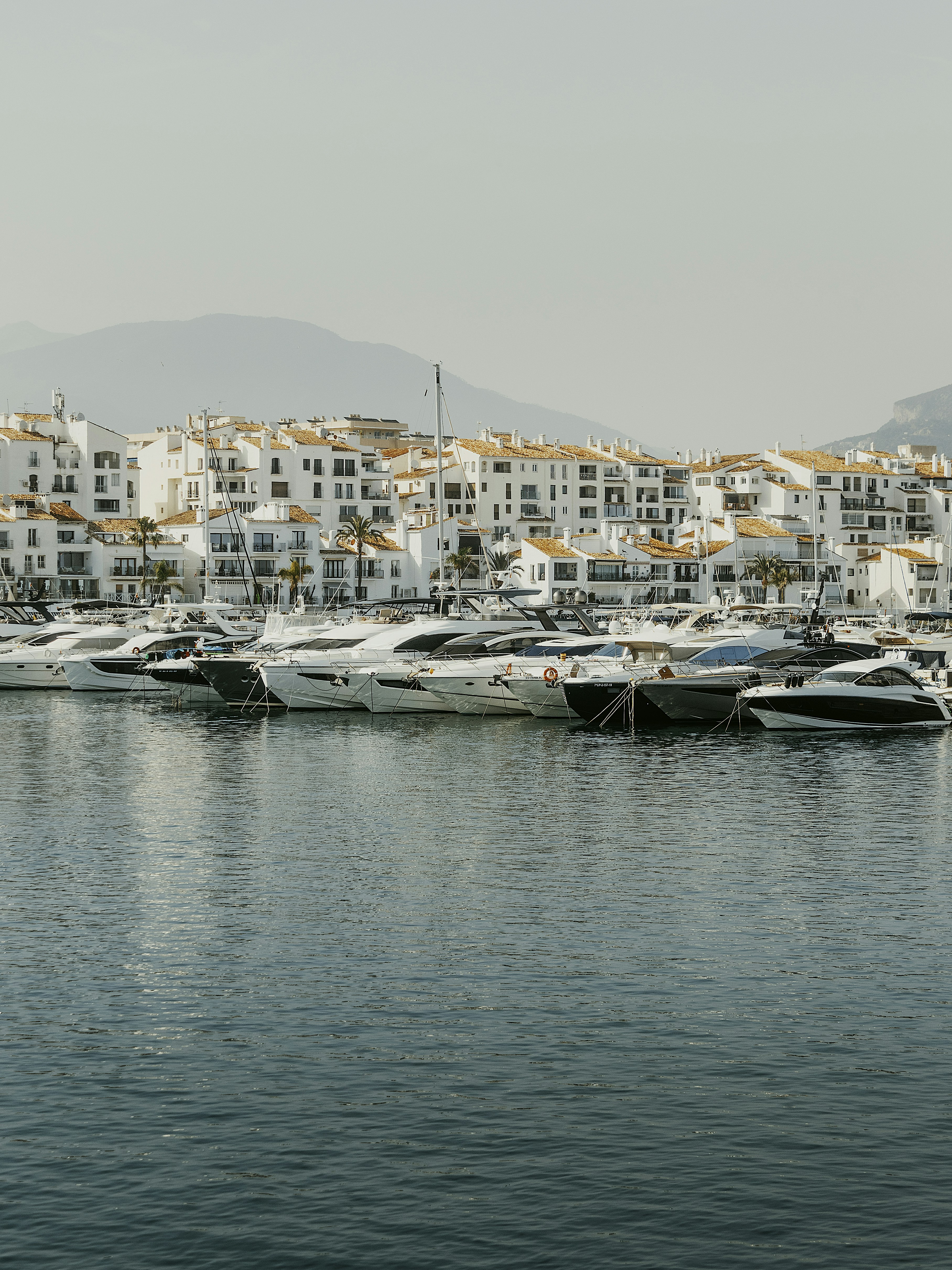 Luxury yachts docked in a white coastal town harbor.