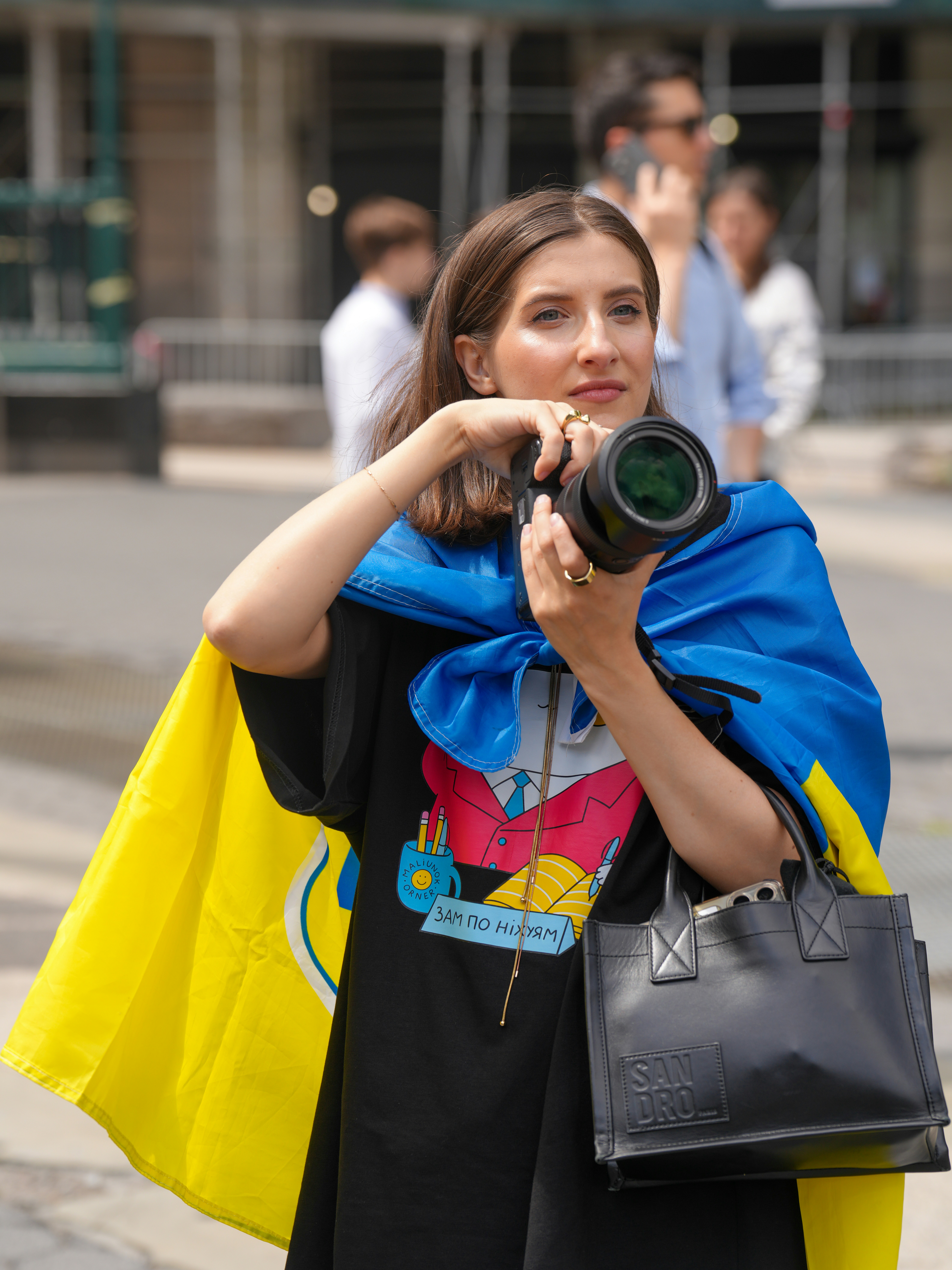 Woman holding camera draped in ukrainian flag