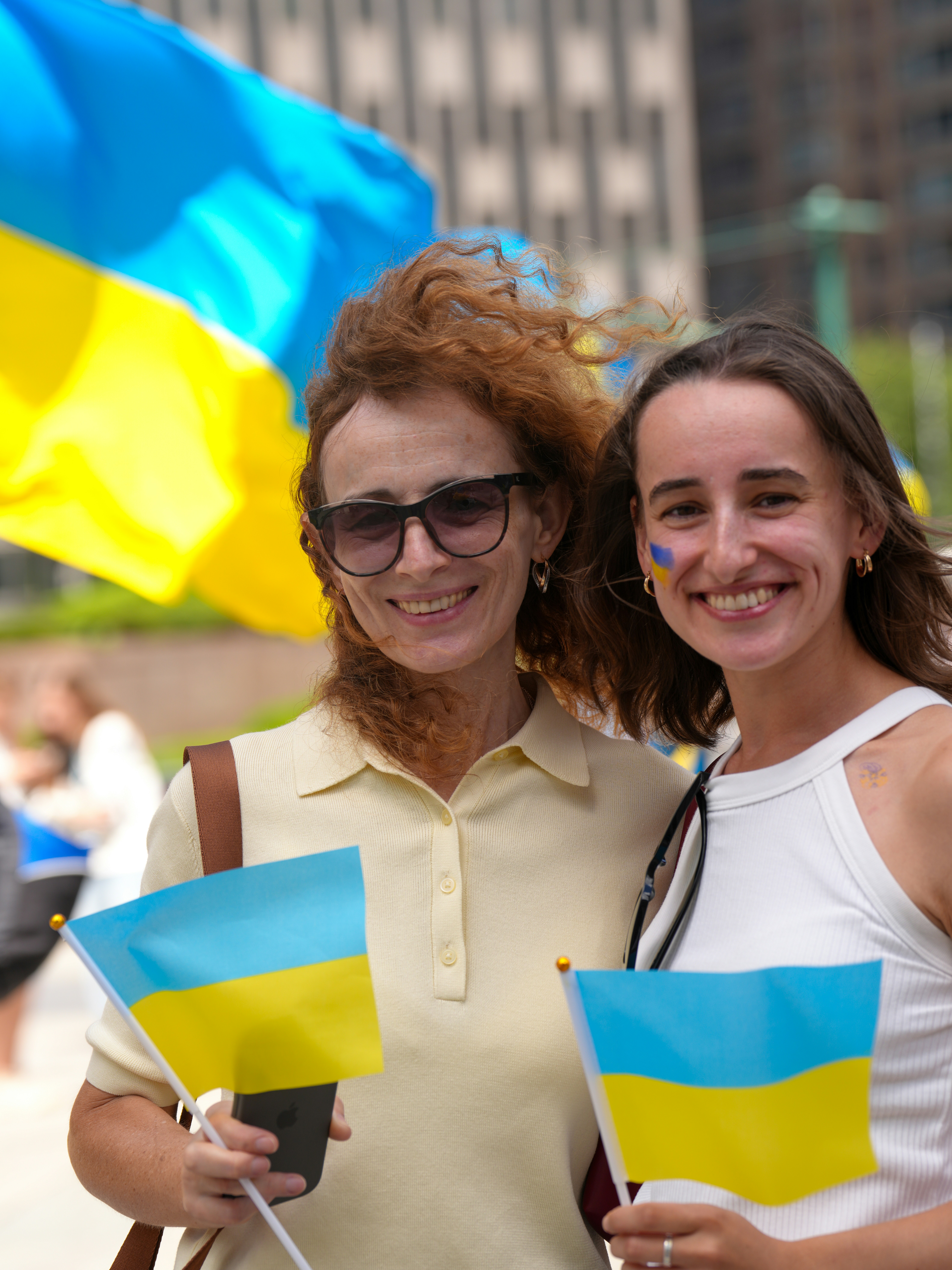 Two women holding ukrainian flags with painted faces.