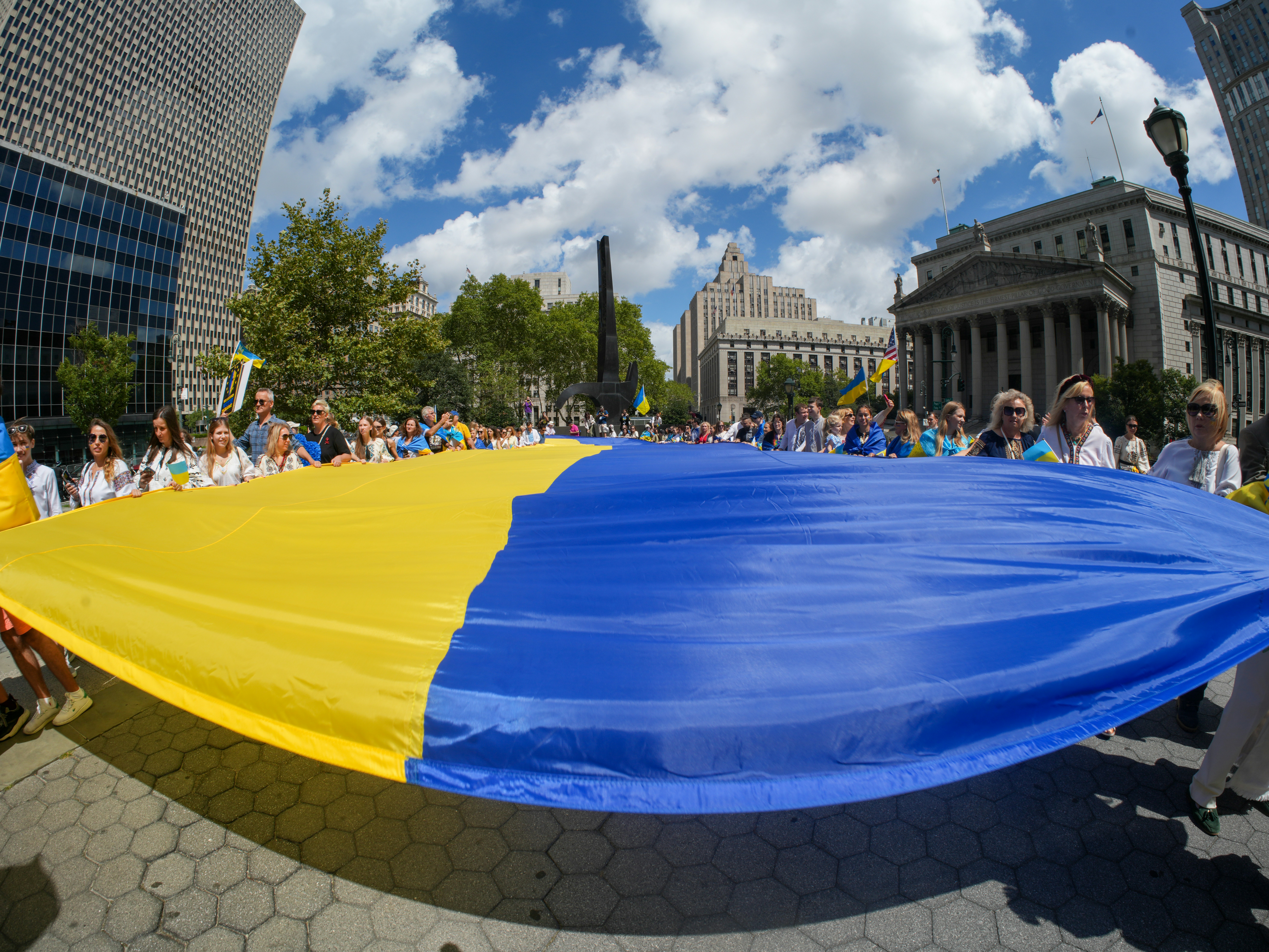 People holding a large ukrainian flag during a rally