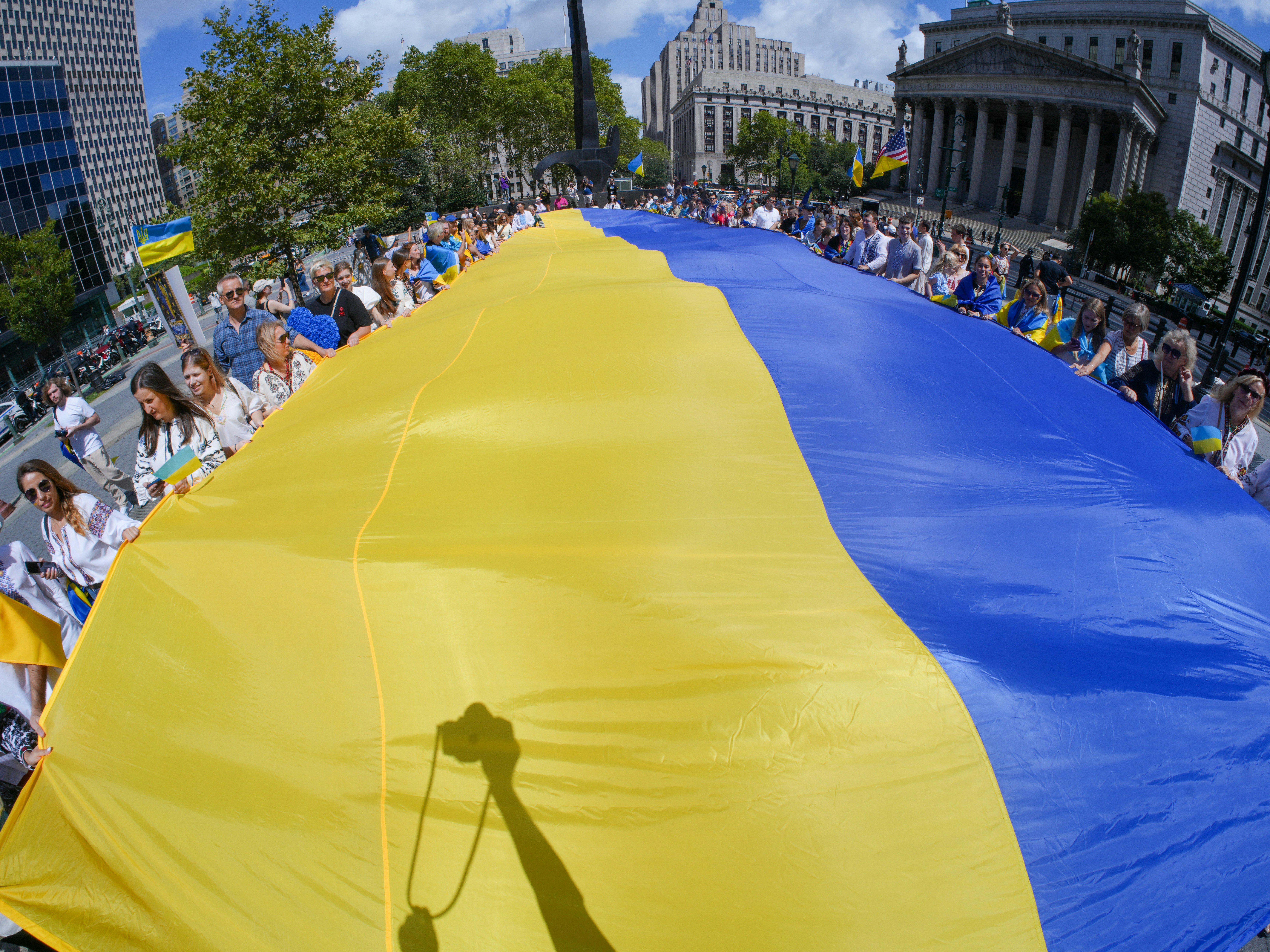 People hold a large ukrainian flag during a demonstration.