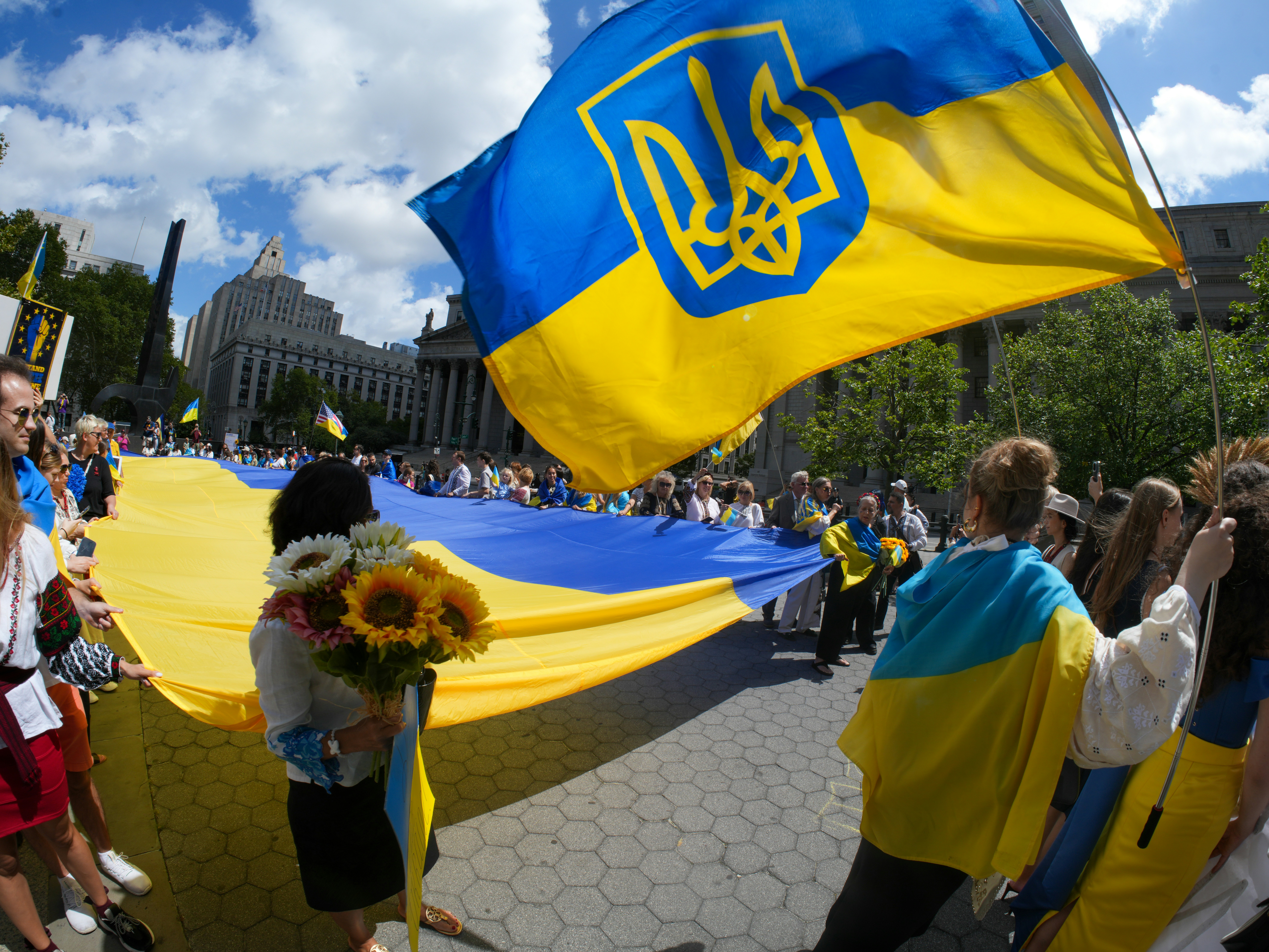 People wave a large ukrainian flag during a rally.