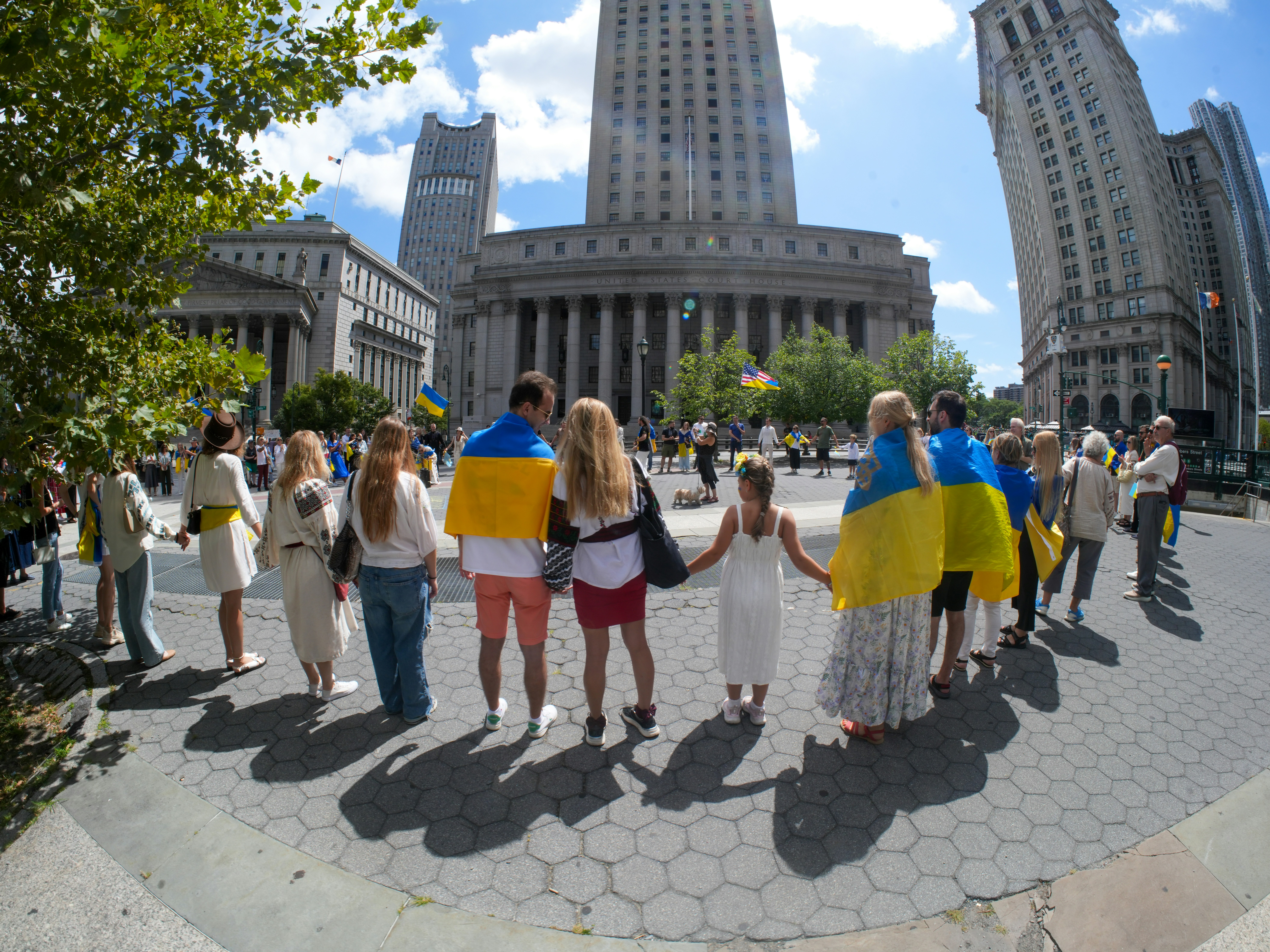 People holding hands in a circle with ukrainian flags